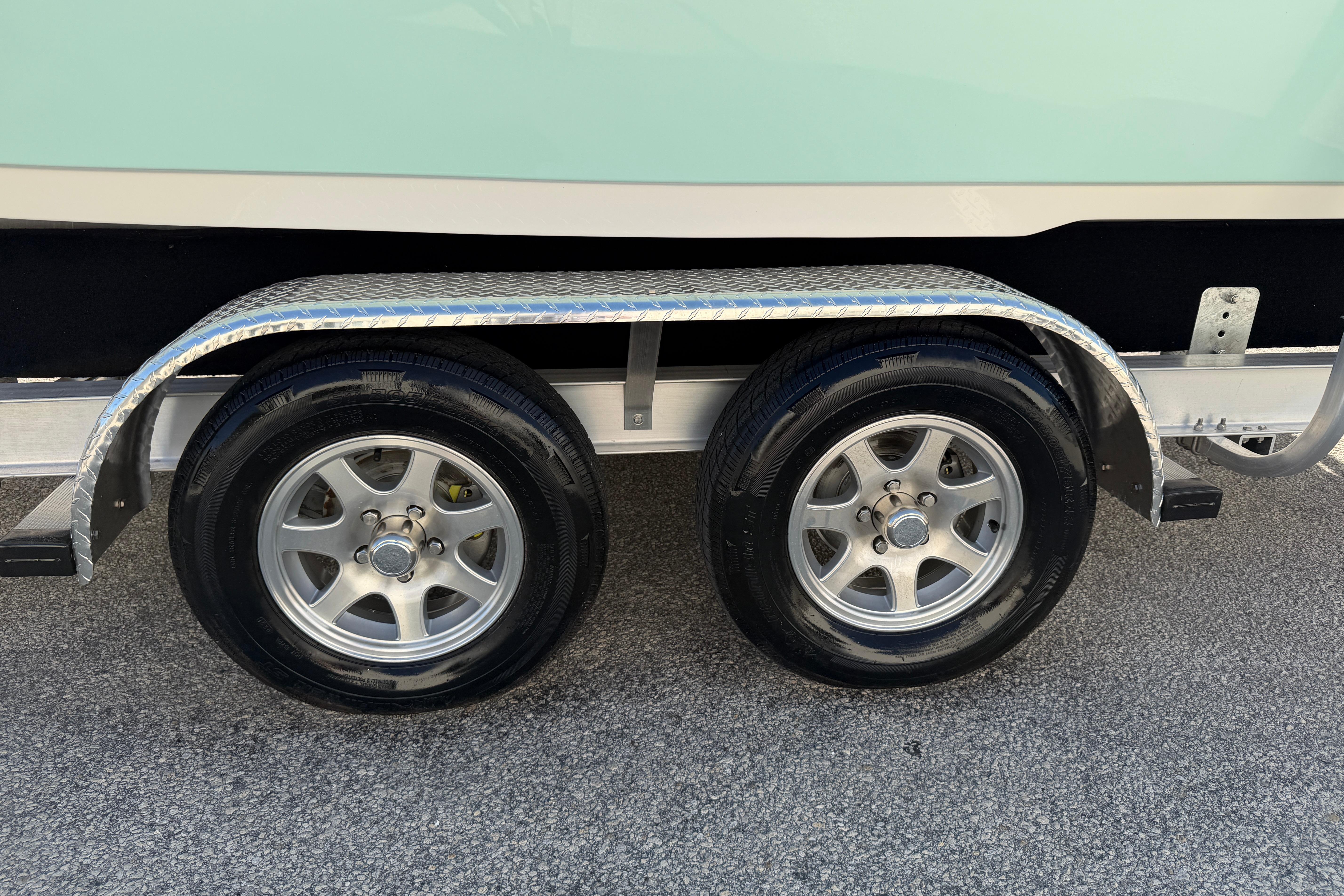Trailer wheels of a 2025 Key West 239 FS boat on pavement.