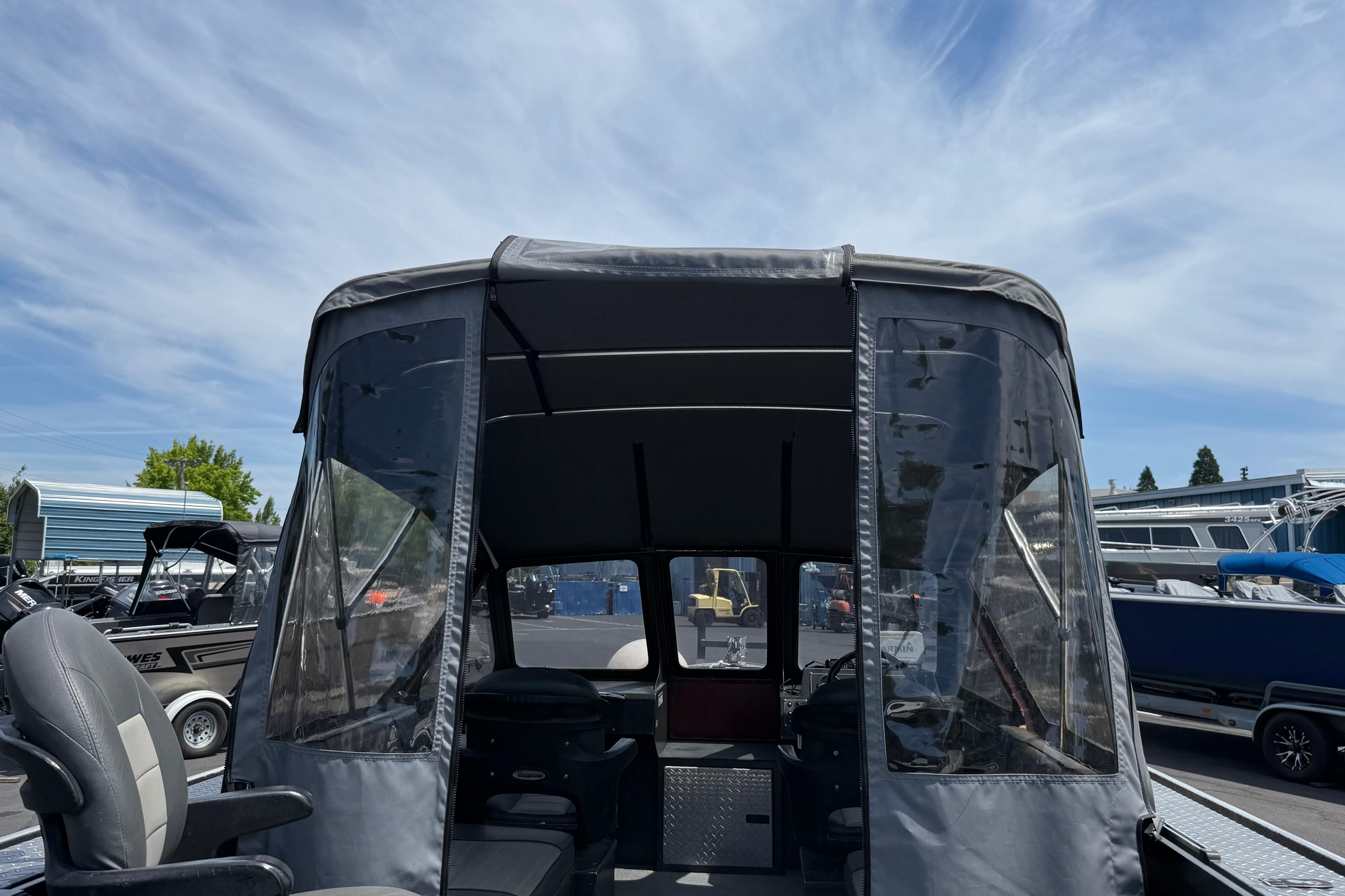 2005 Willie Raptor 21' boat with canopy, parked outdoors under a clear sky.