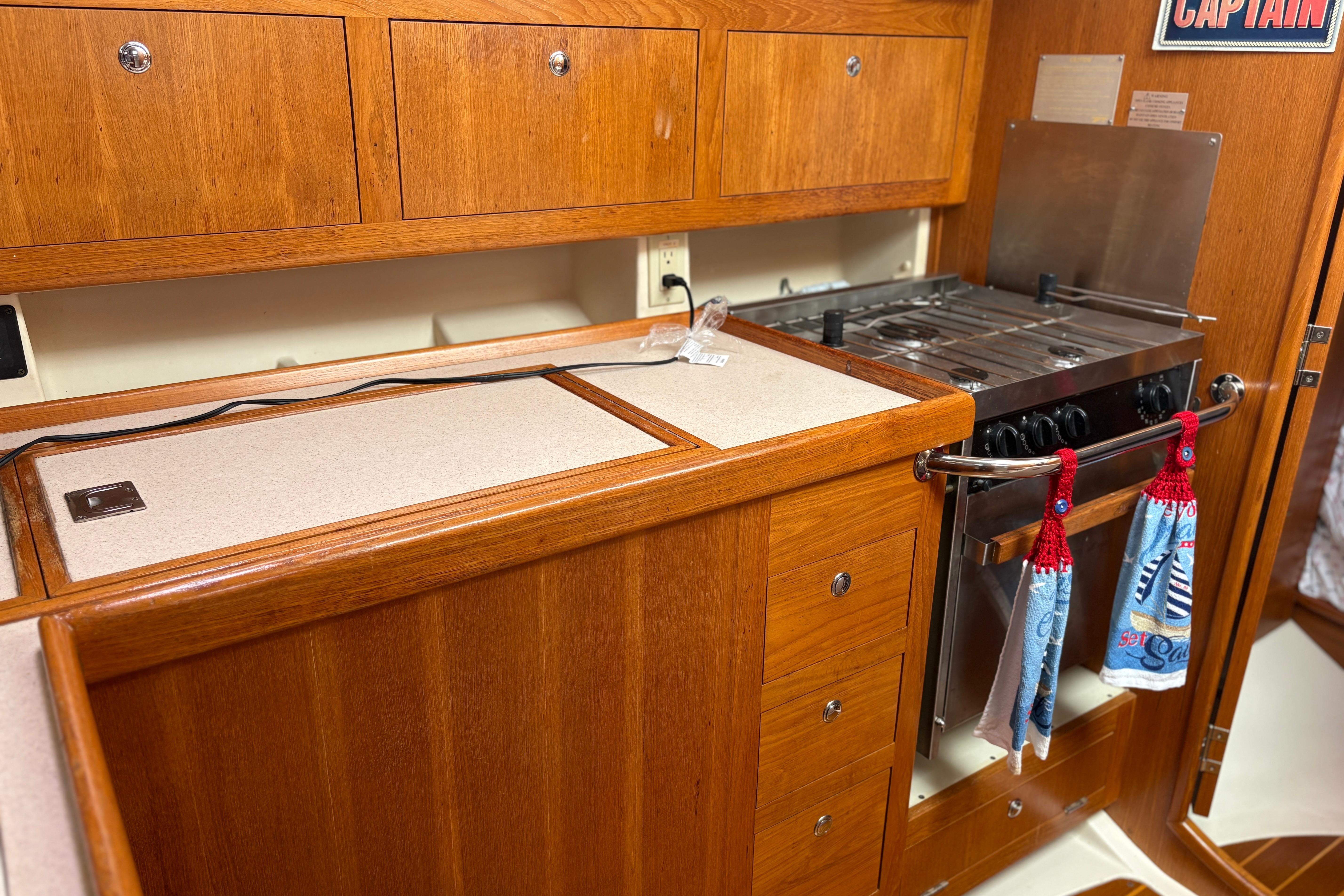 Wooden kitchen interior of 2002 Hunter 386 yacht with stove and storage cabinets.