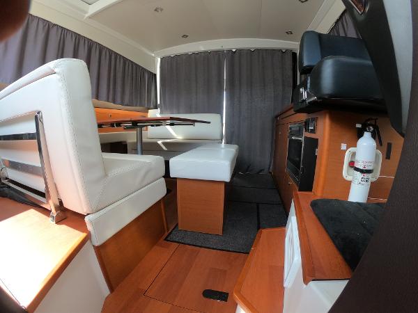 2017 Jeanneau NC 11 interior with white seating, wooden flooring, and dining area.