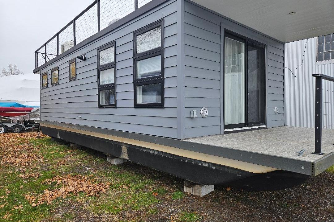 Modern 2021 East Coast Houseboats Freedom 40 with sleek gray exterior and large windows.