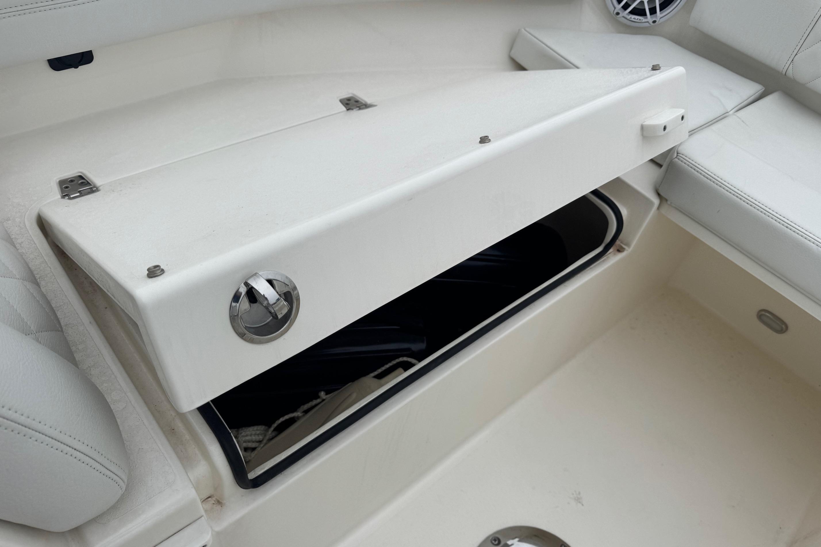 2024 Cobia 240 Dual Console boat storage compartment with open lid.