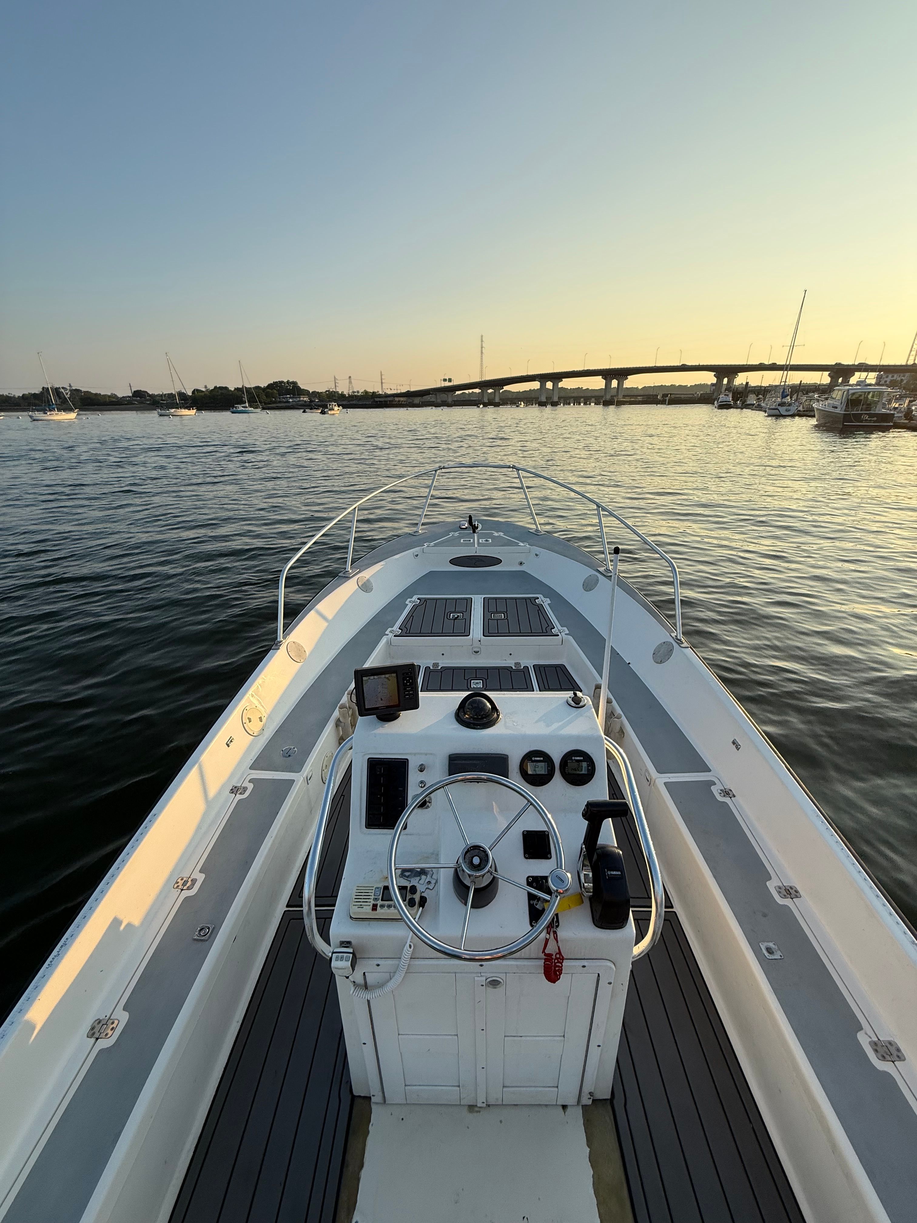 Custom Sea Fly 2004 boat on calm water at sunset, with bridge in background.