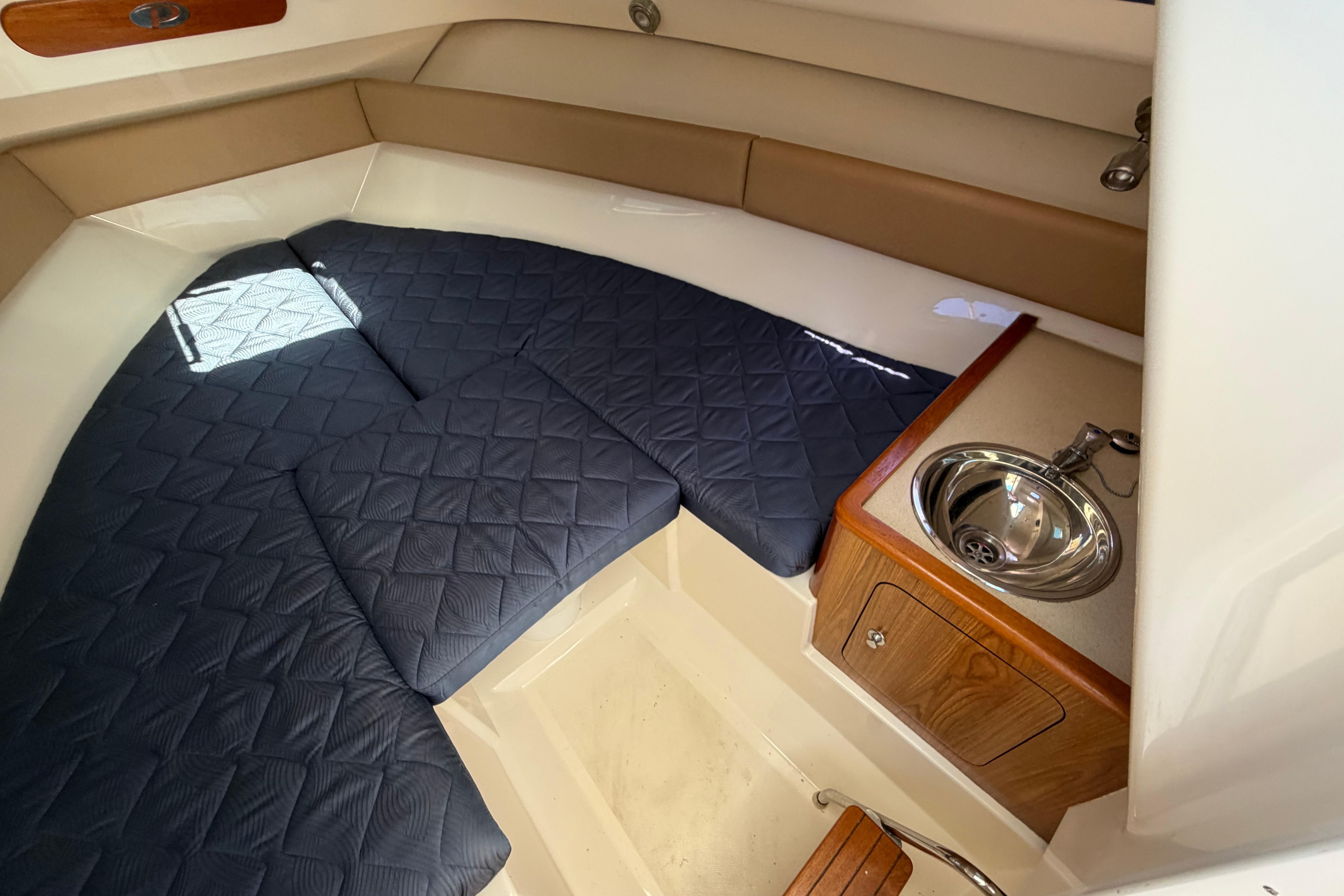 2010 Pursuit OS 255 Offshore cabin interior with cushioned seating and compact sink.