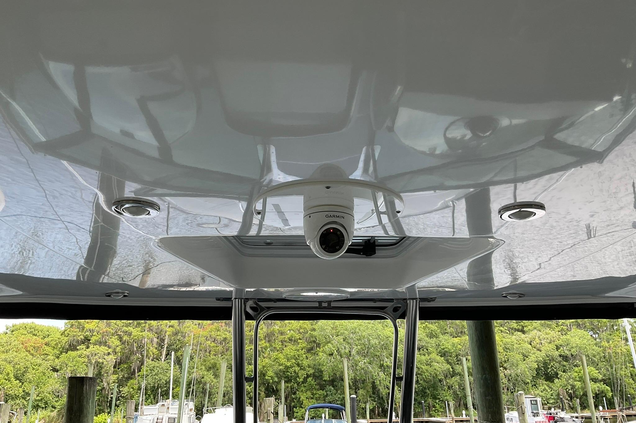 2019 Monterey 335 Sport Yacht with Garmin camera on deck, docked near lush greenery.
