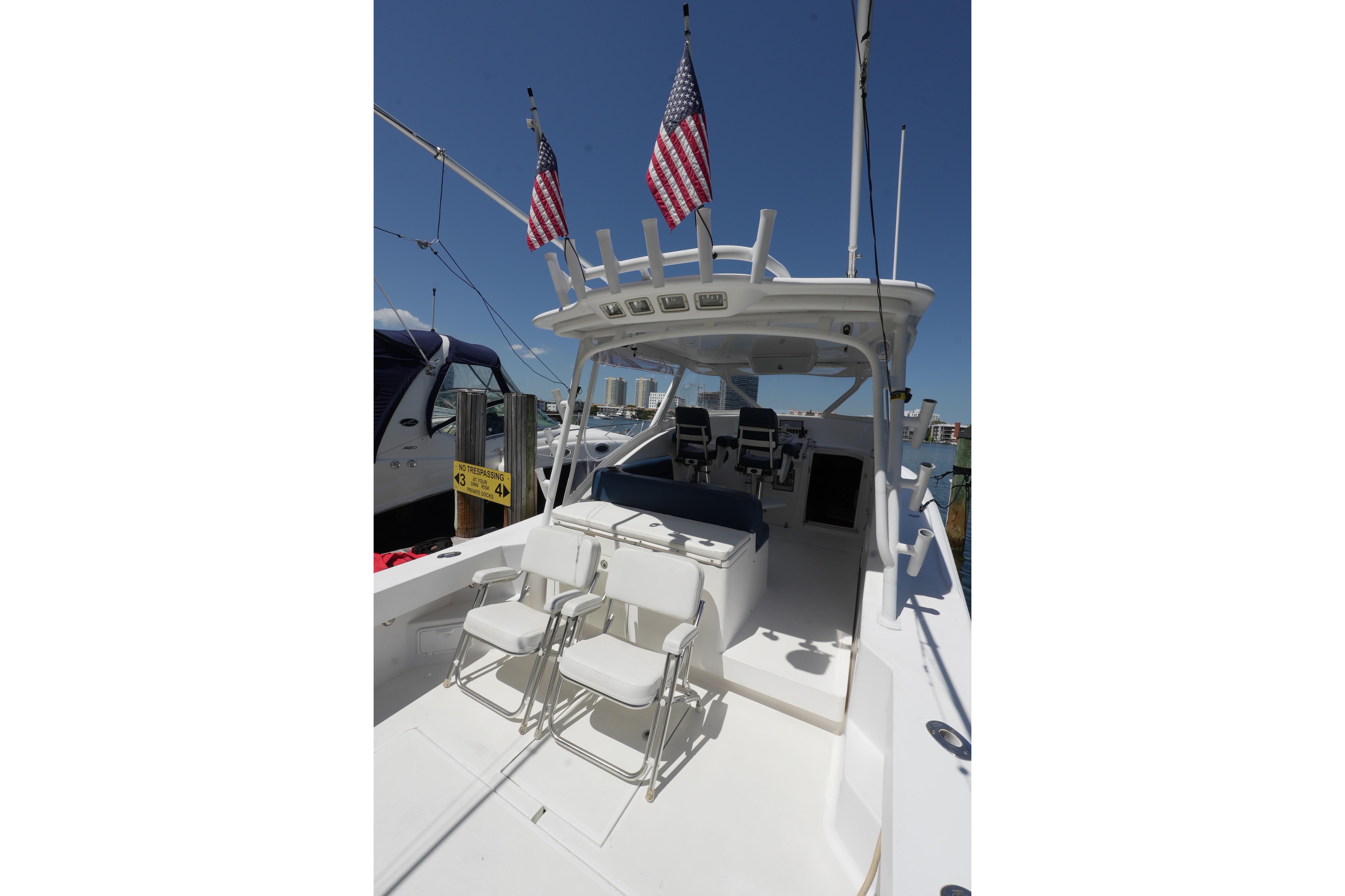 Custom Carolina 34 boat, 2012 model, with seating and American flags, docked under clear skies.