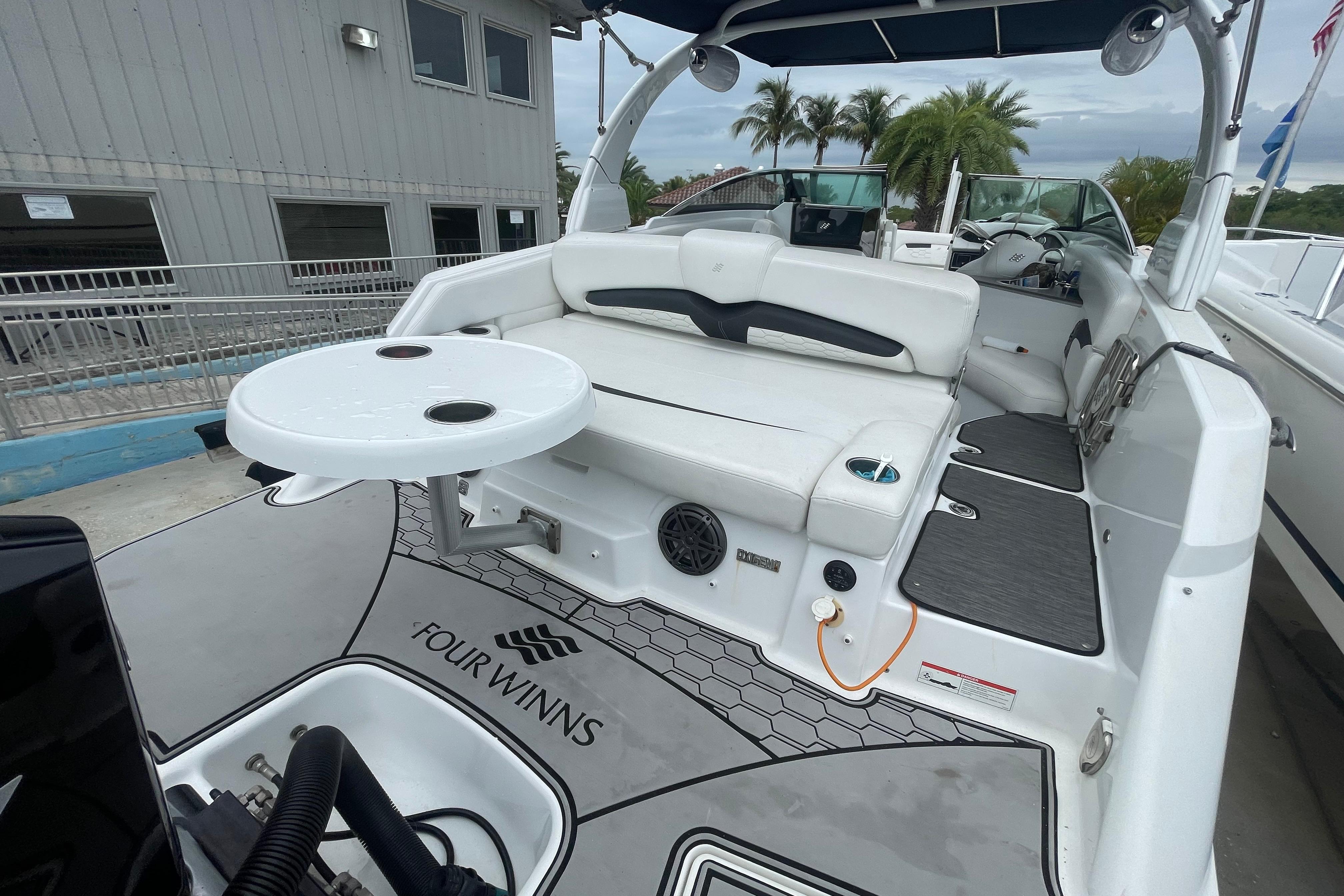 2022 Four Winns HD8 OB boat with white seating and a round table on deck.