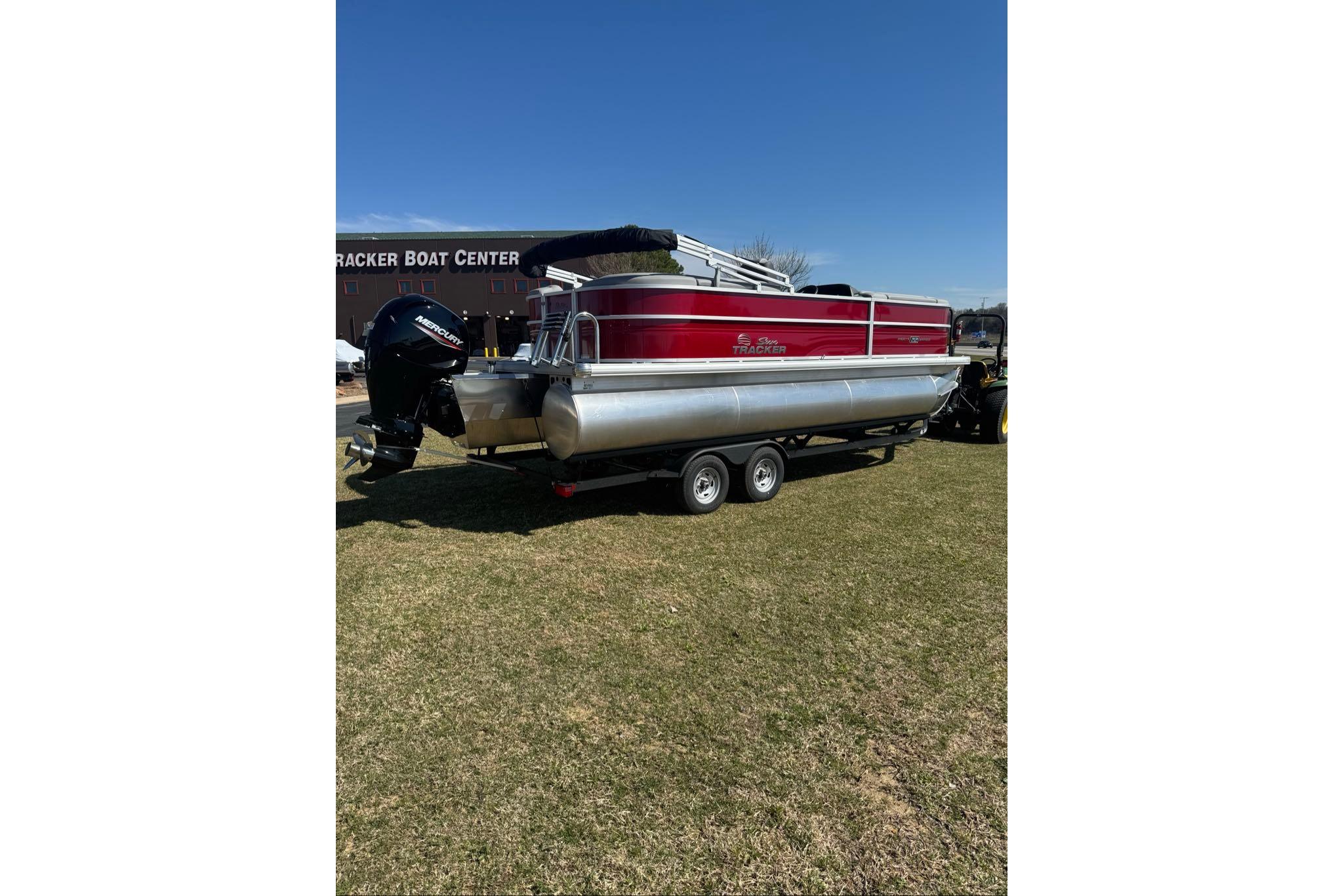 2026 Sun Tracker Party Barge 22 XP3 pontoon boat on trailer, parked on grass.