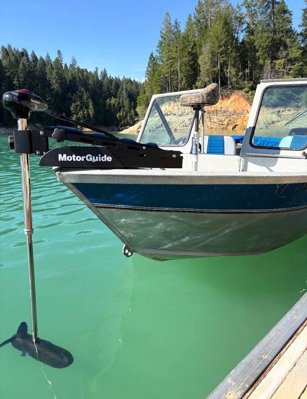 A blue and white 2002 Stryker Rogue with a MotorGuide motor on green water.