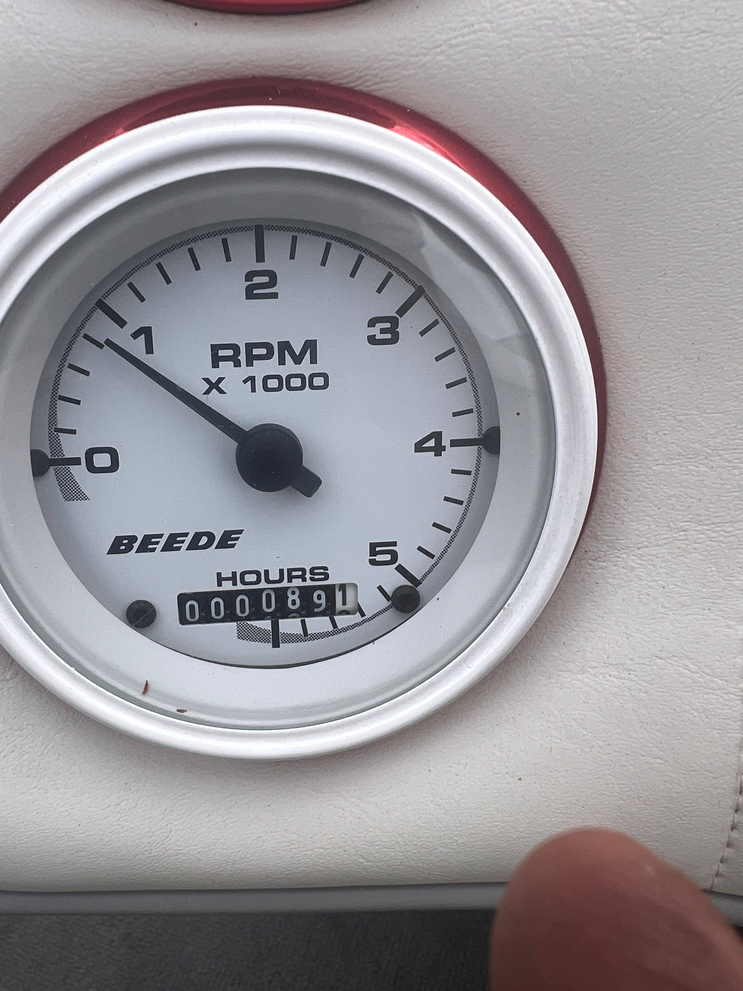 Close-up of a tachometer with red accents, showing 891 operating hours.