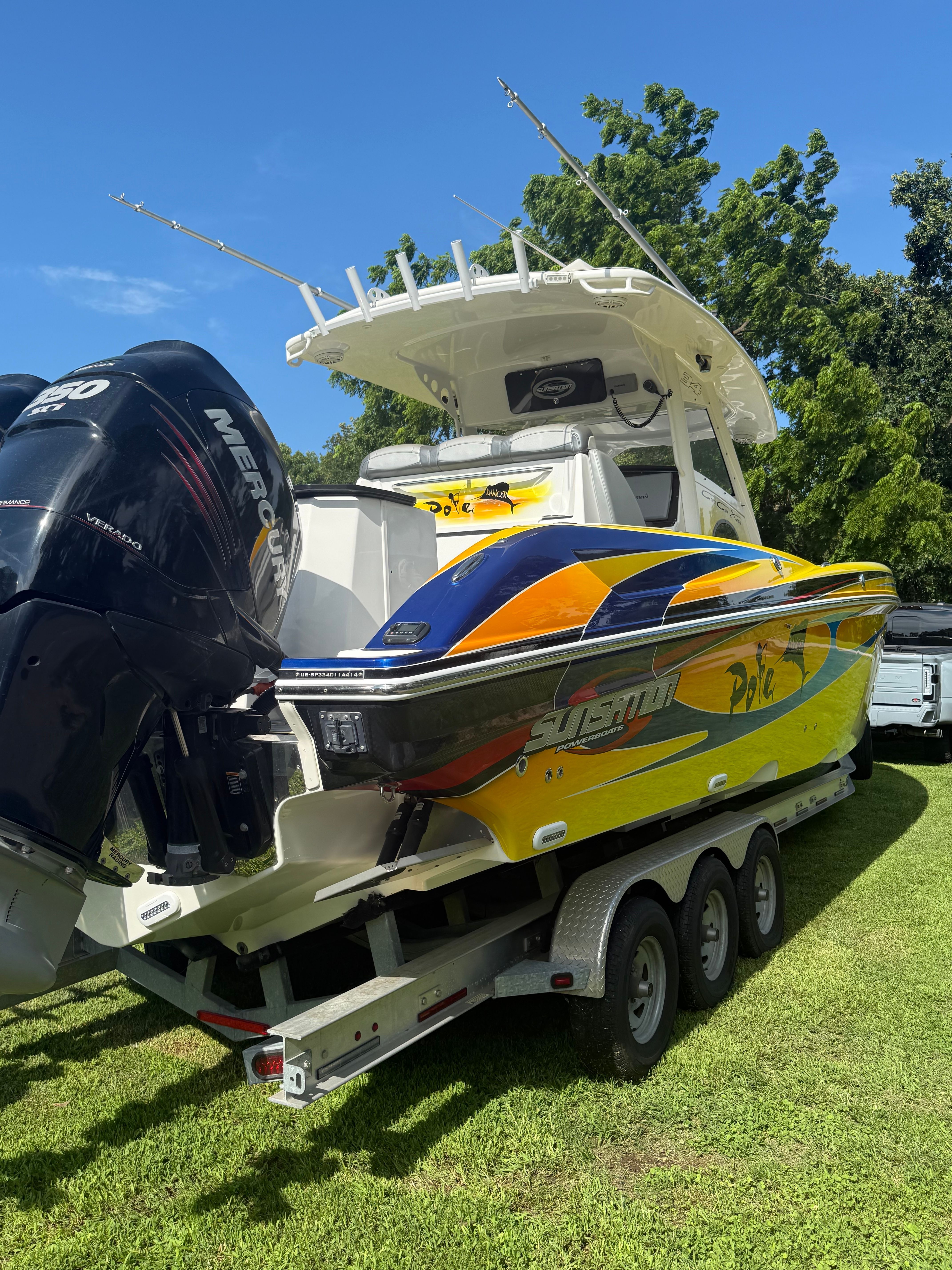 A colorful boat on a trailer, featuring powerful outboard engines and a spacious deck.