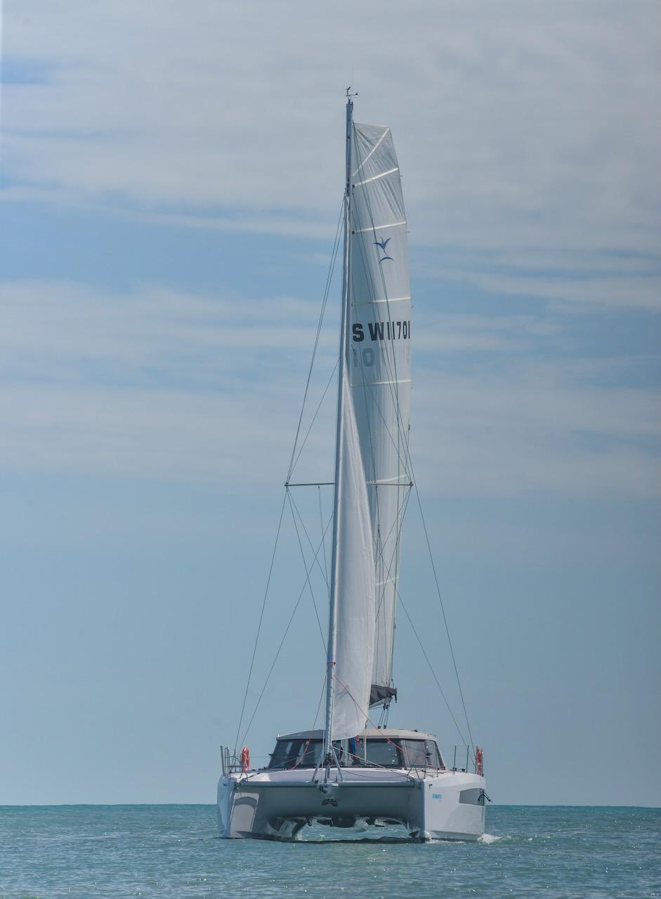 2025 Seawind 1170 catamaran sailing on calm ocean under clear sky.