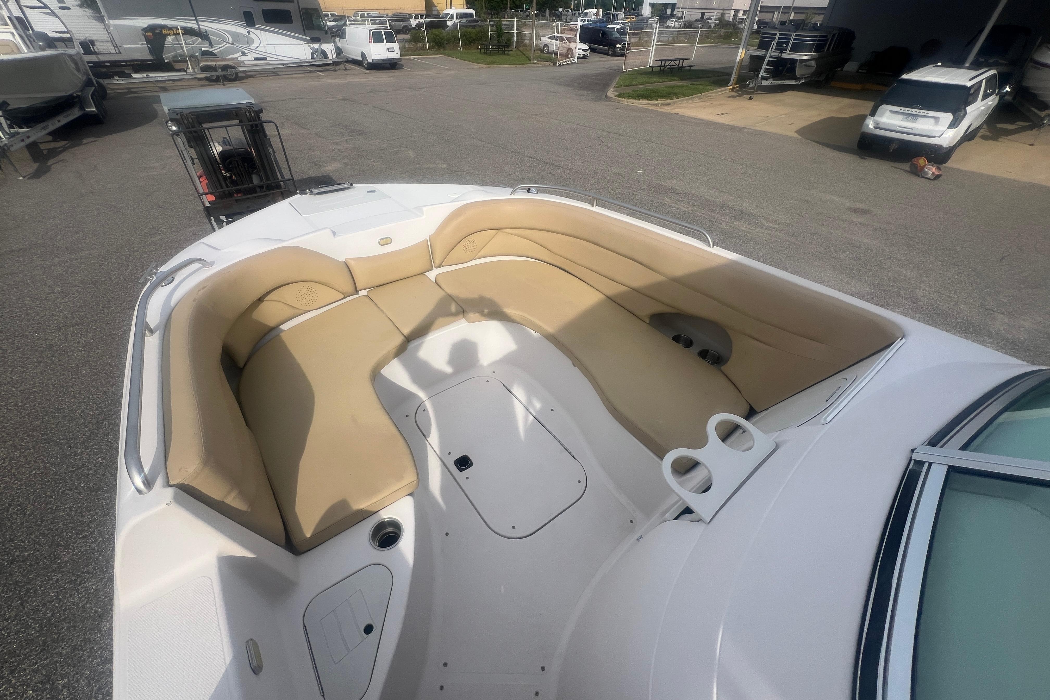 2002 Hurricane SunDeck 260 OB boat with spacious seating and cup holders in a parking area.