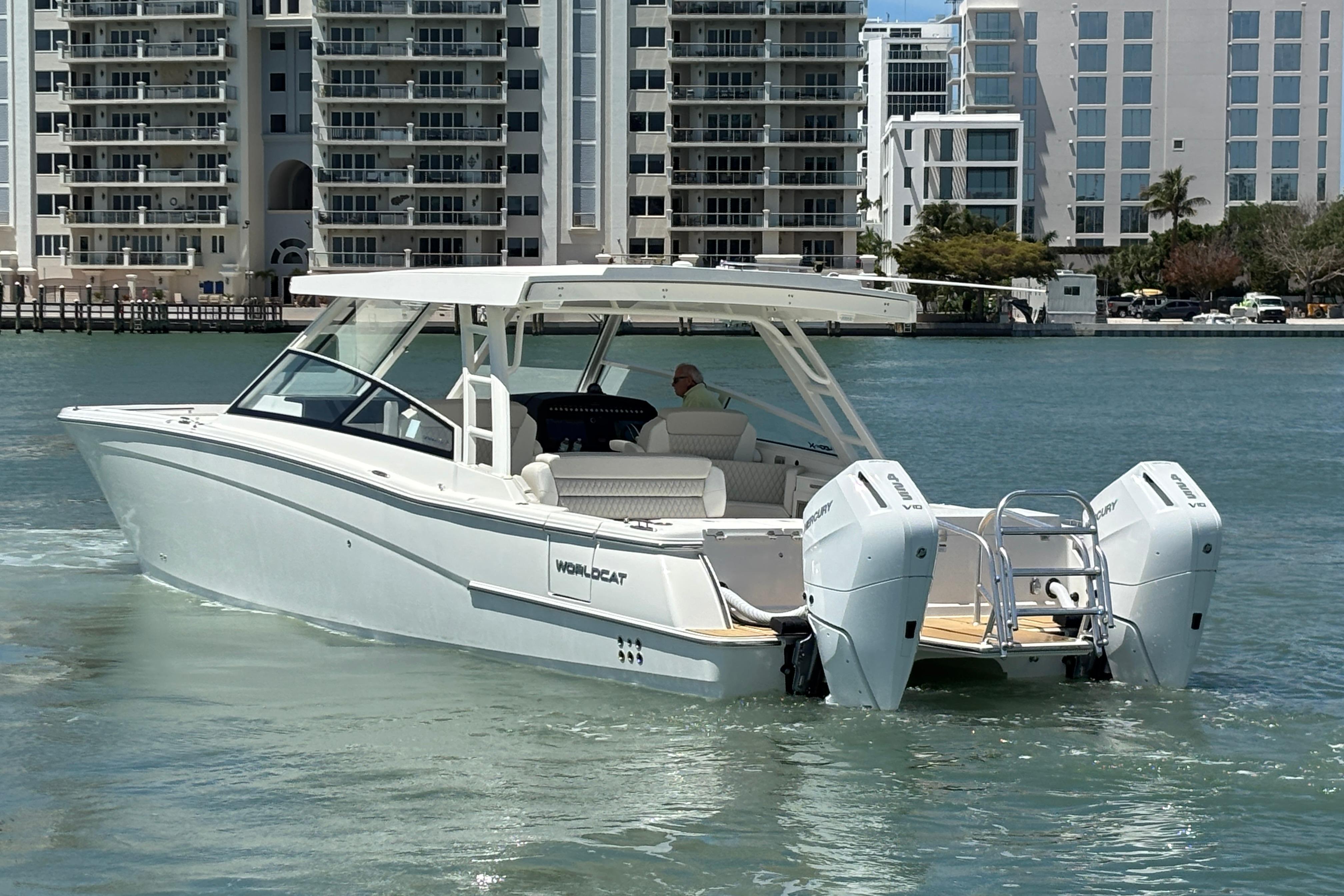 2026 World Cat 400 DC-X Island boat cruising near modern waterfront buildings.