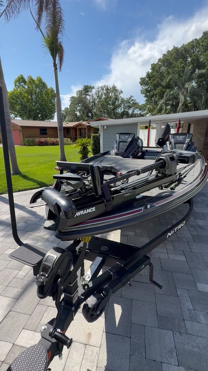 A 2024 Nitra Boats 21 XL Pro on a trailer in a sunny residential area.