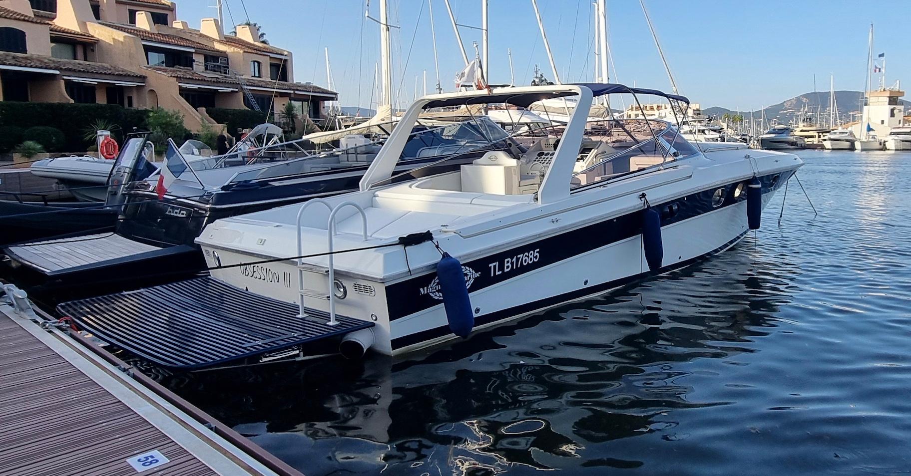 1990 Magnum 40 boat docked in a marina, surrounded by other vessels and waterfront buildings.