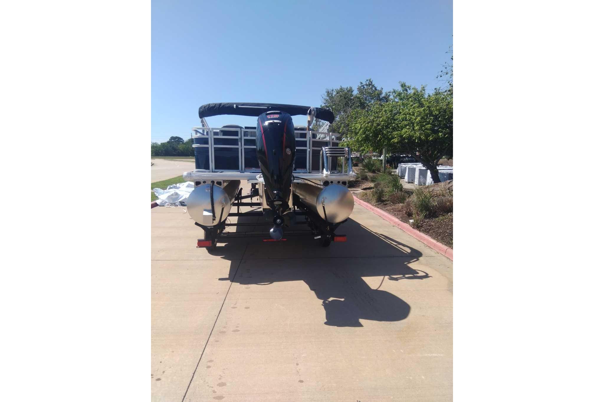 2026 Sun Tracker SportFish 20 DLX pontoon boat on a trailer, parked outdoors.