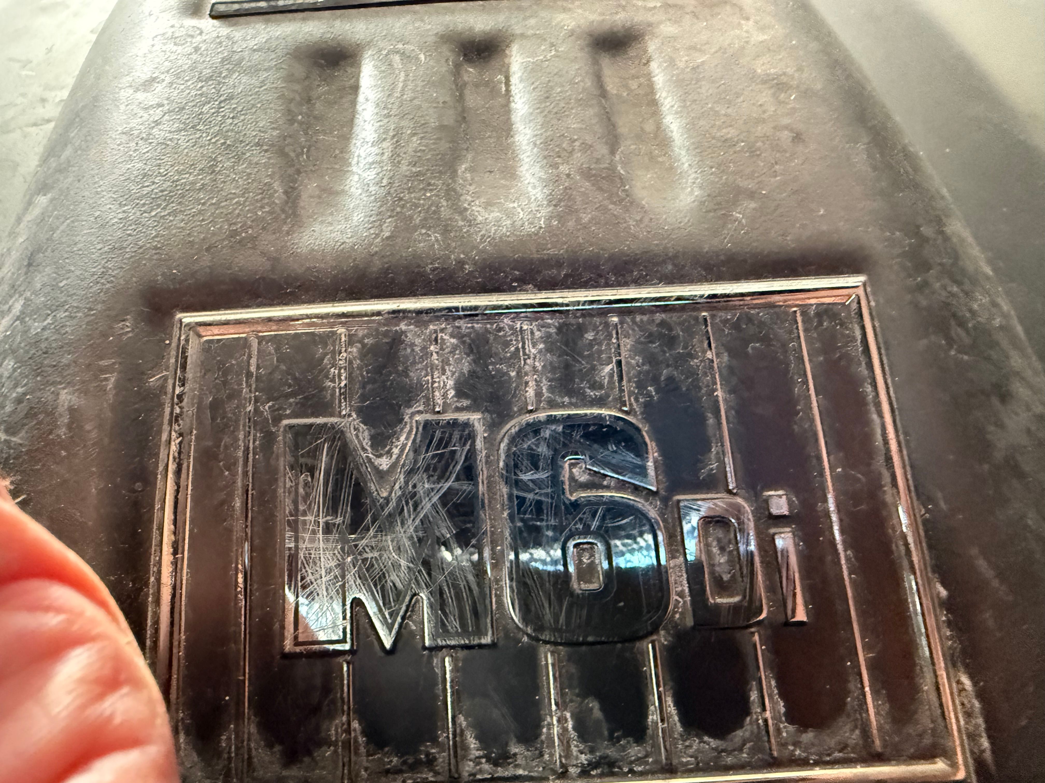 Close-up of an M6Di engine cover detail with scratches.