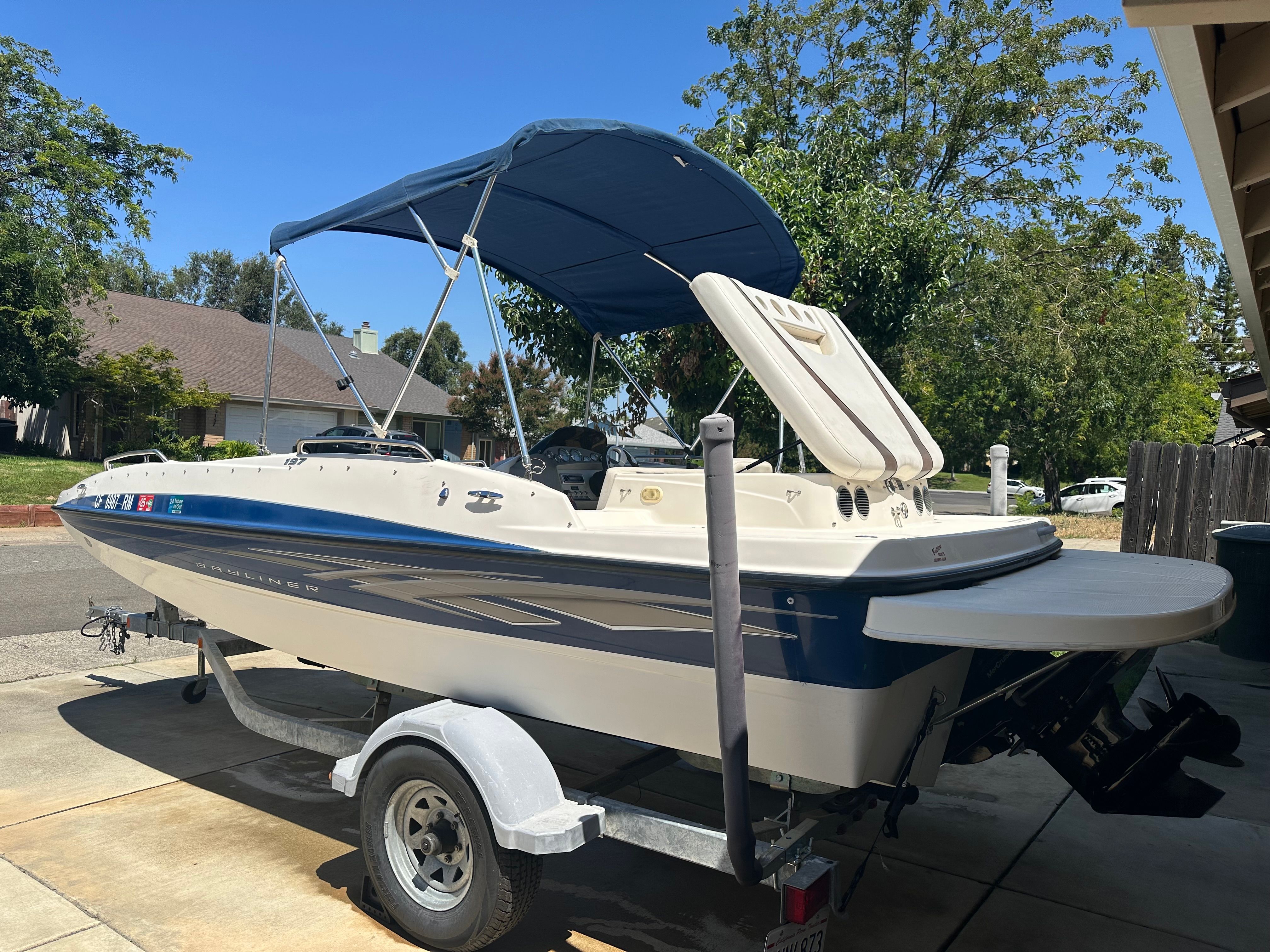 A 2008 Bayliner boat is on a trailer in a driveway.