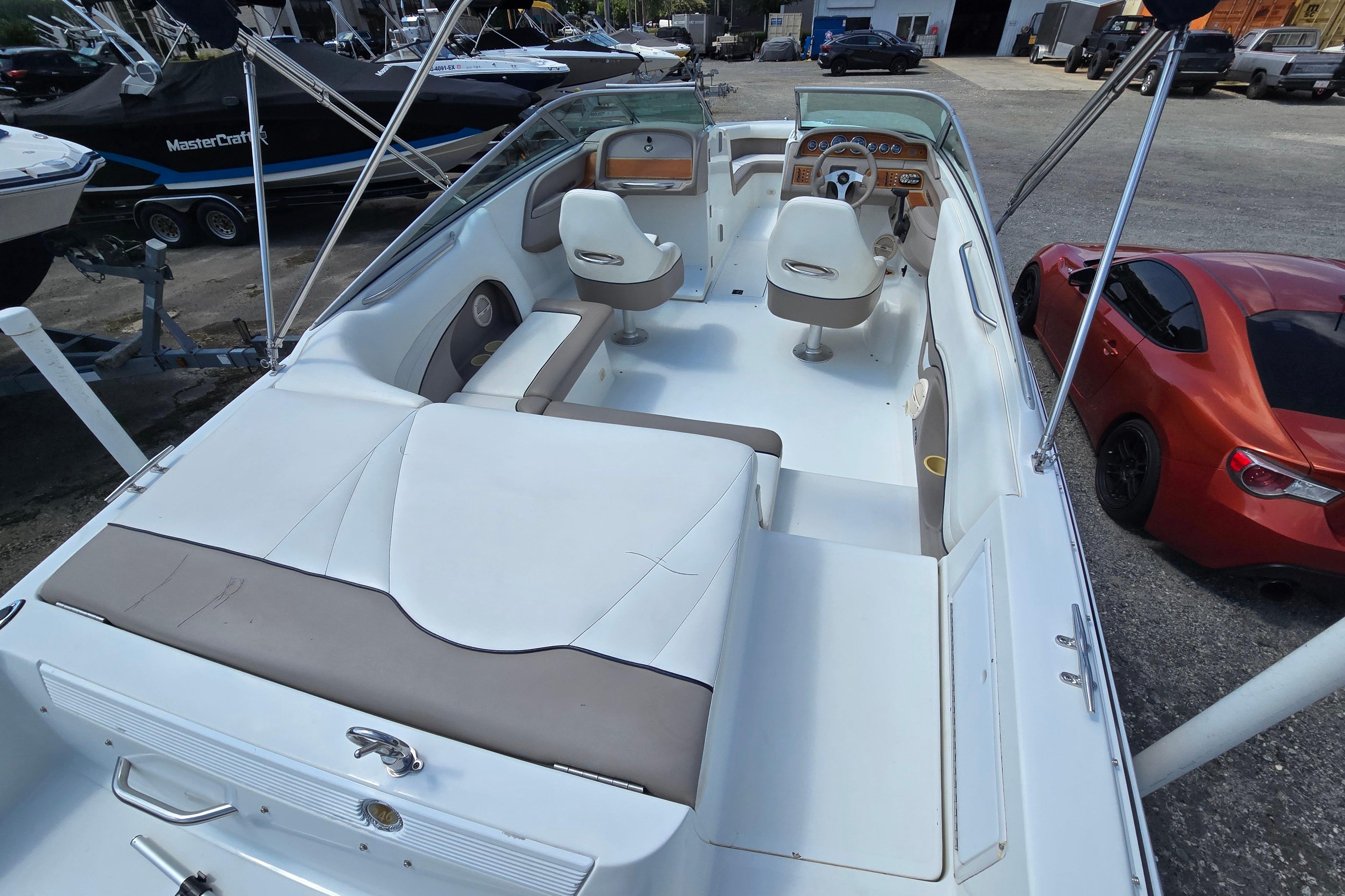 2000 Cobalt 246 boat interior with white seating and dashboard, parked near a red car.