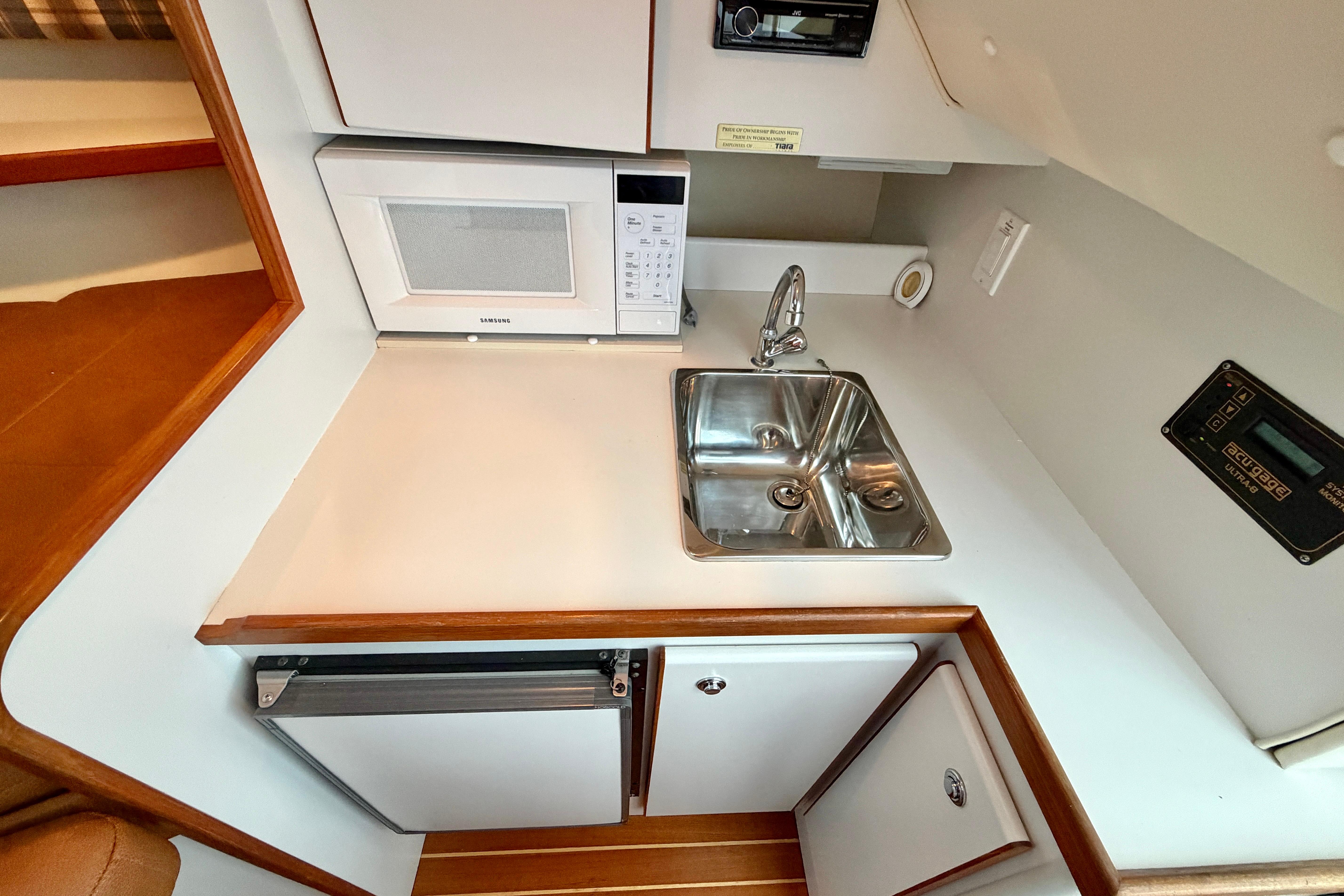 Compact galley in 1999 Tiara Yachts 2900 Coronet with sink, microwave, and fridge.