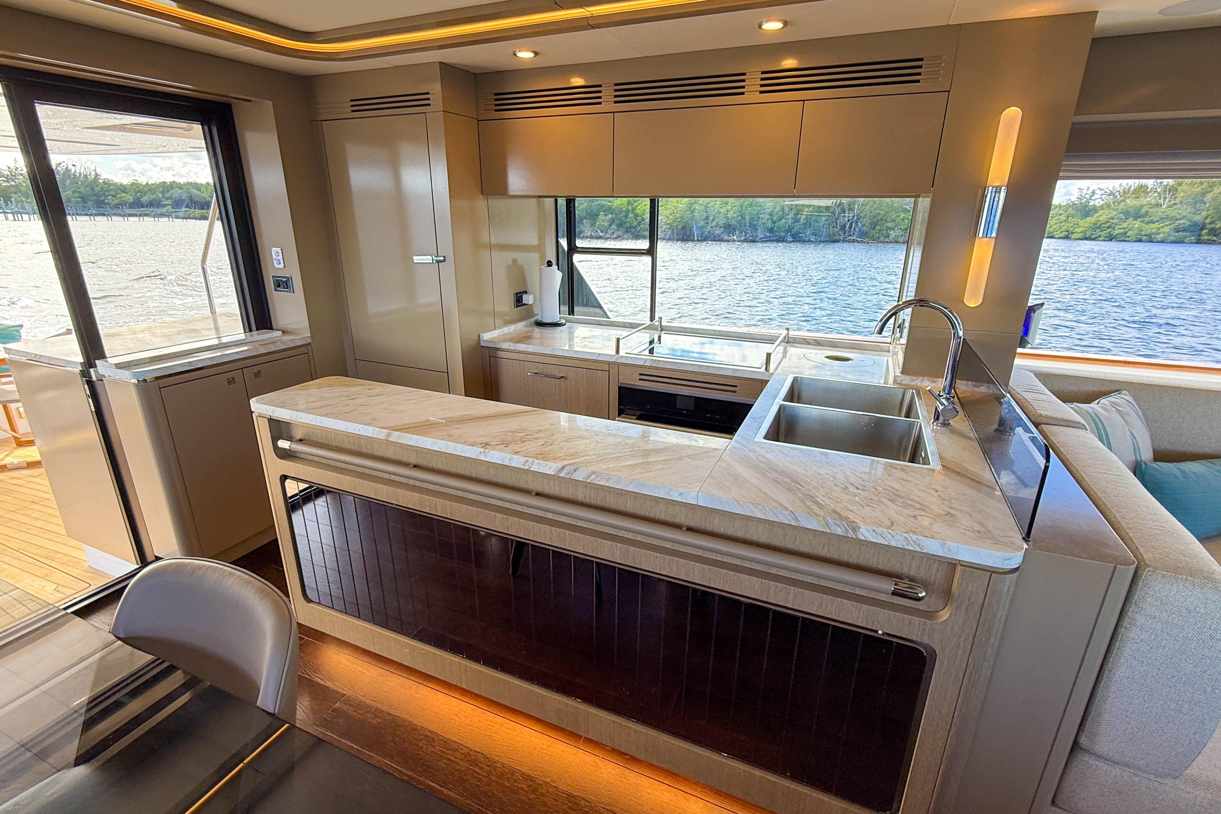 Luxurious interior of 2023 Sirena 68 yacht with modern kitchen and scenic water view.