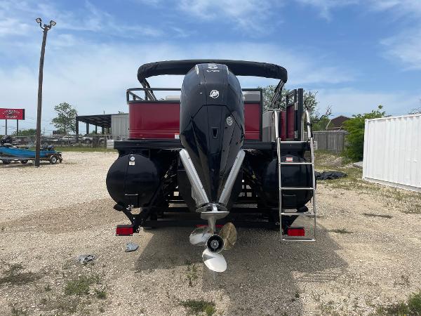 2023 Regency 250DL3 pontoon boat with outboard motor, parked on gravel lot.