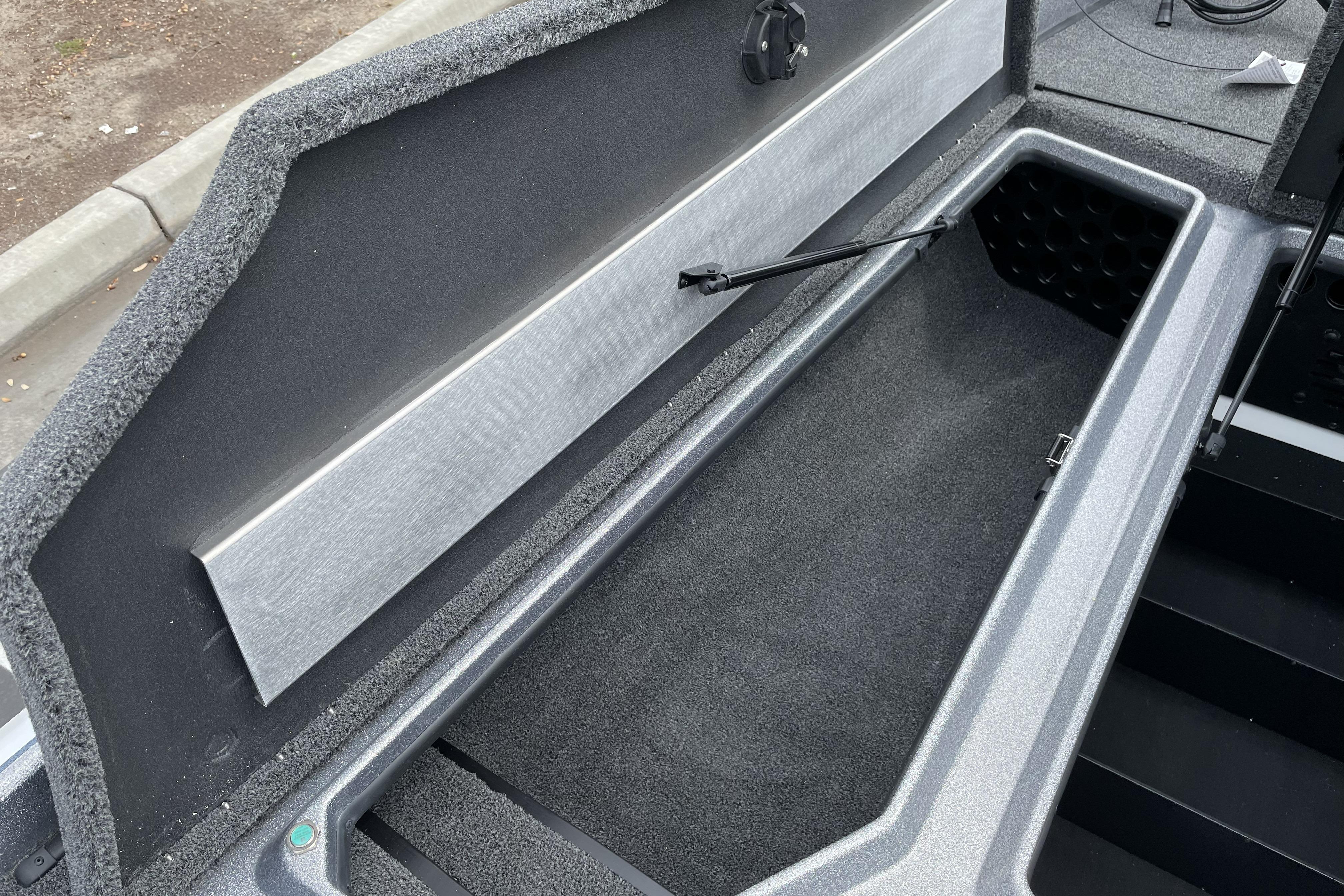 Open storage compartment in 2026 Nitro Z21 XL boat, featuring carpeted interior and hydraulic lift.