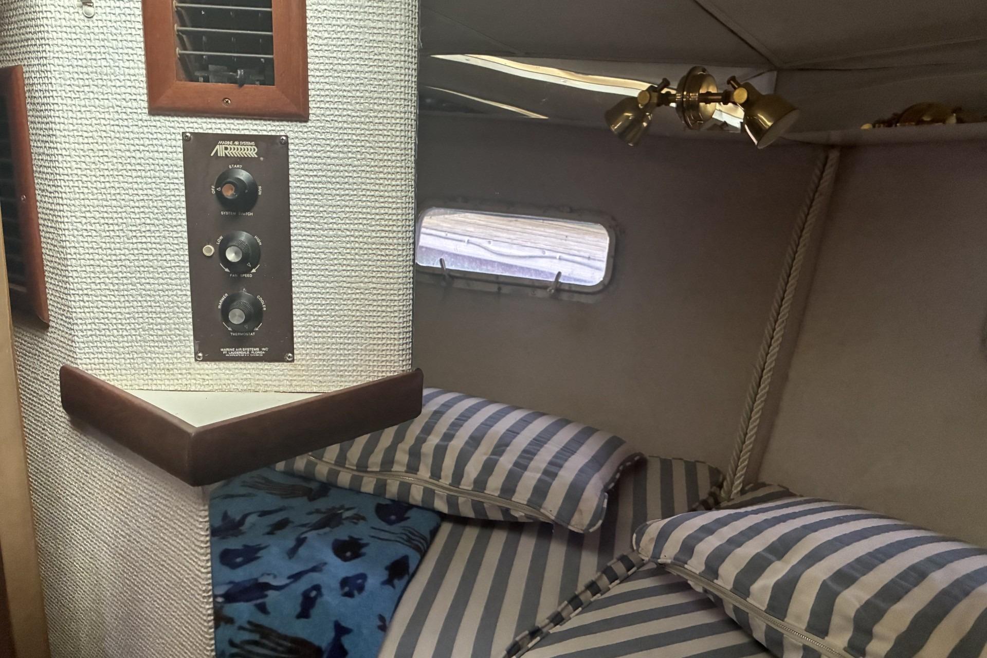 Interior cabin of 1980 Chris-Craft 360 Commander with striped bedding and control panel.