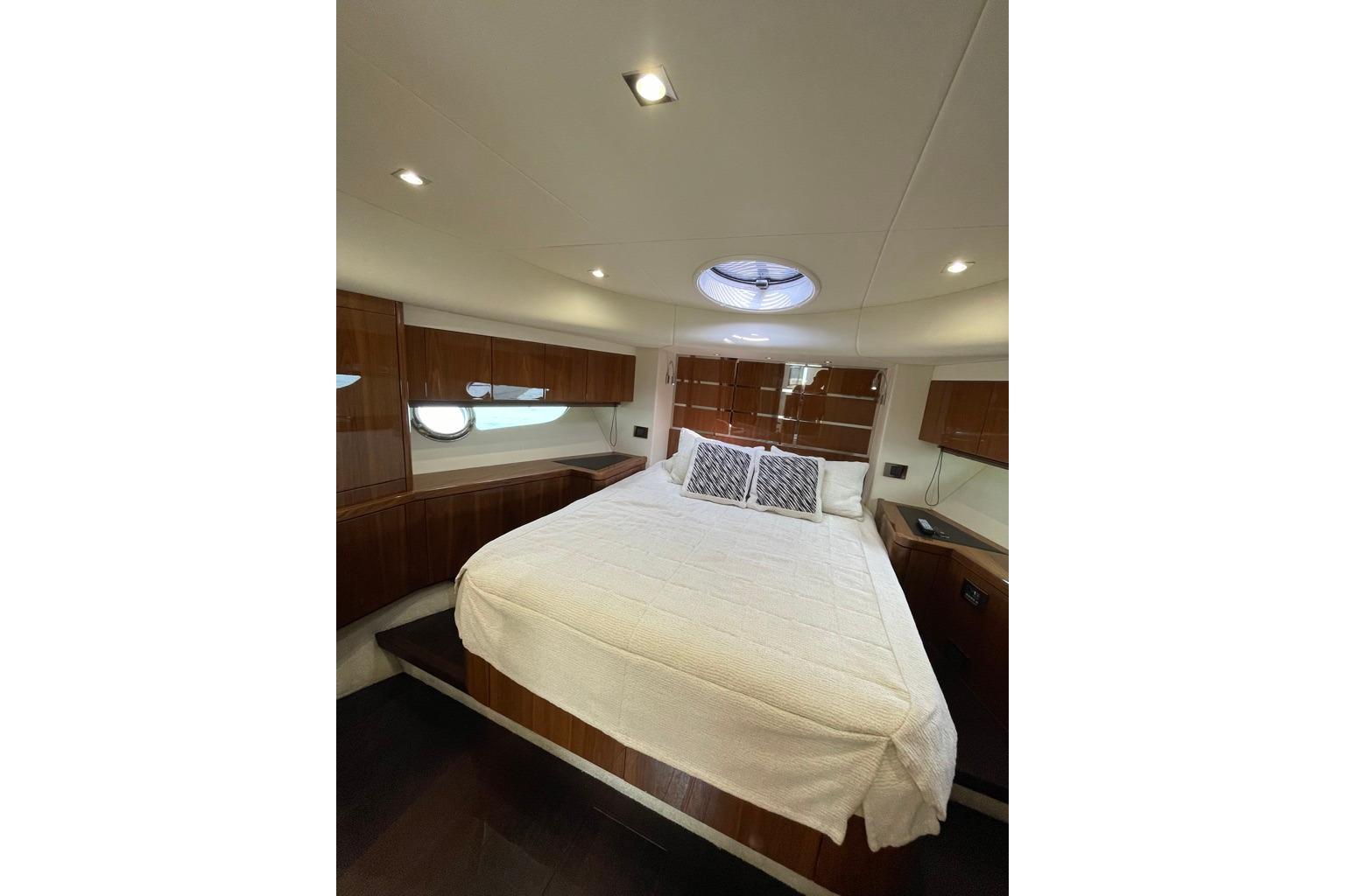 Luxurious bedroom interior of 2016 Sunseeker Manhattan 65 yacht with elegant wood finishes.