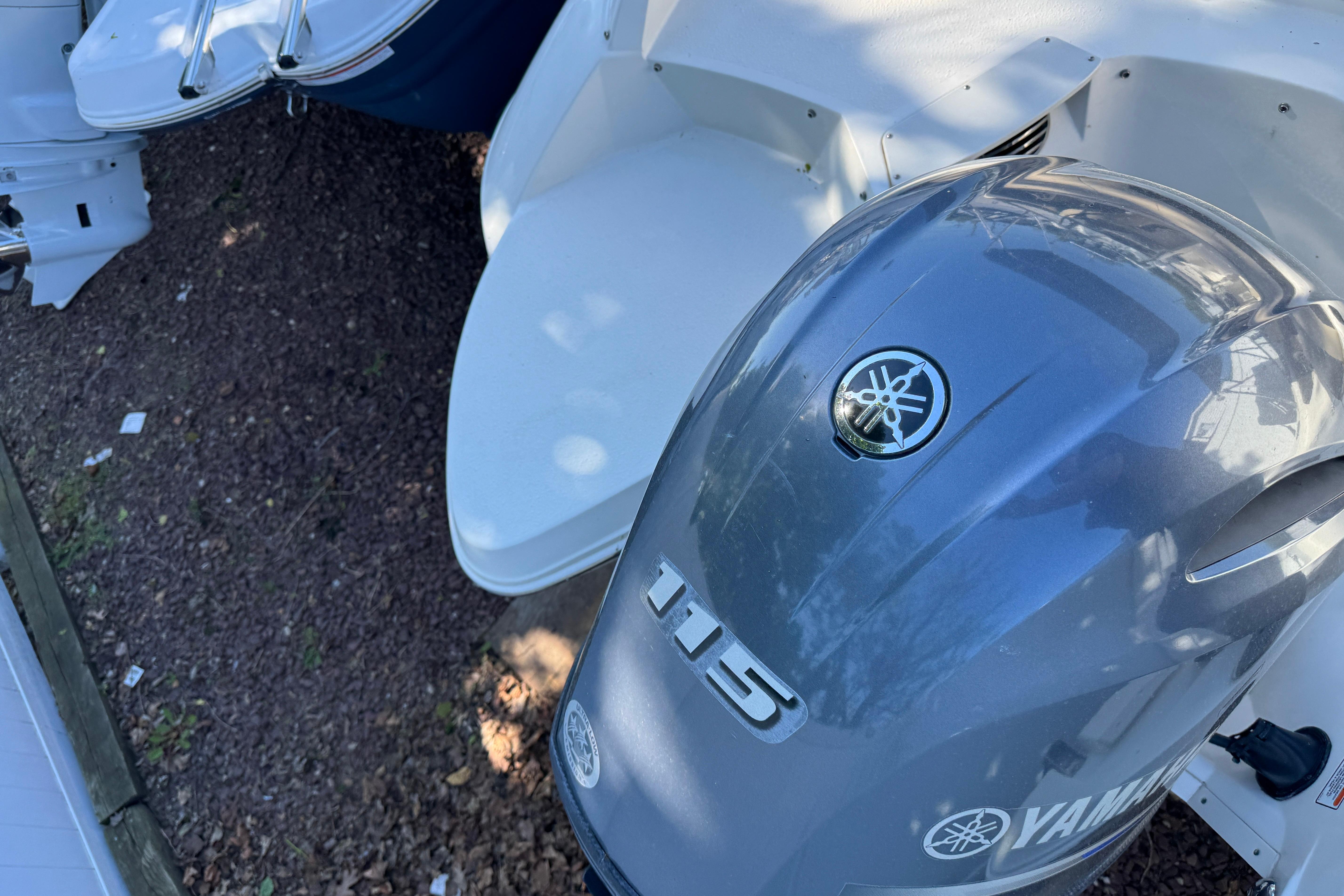 2018 Stingray 204 LR boat with Yamaha 115 outboard motor, docked on gravel.