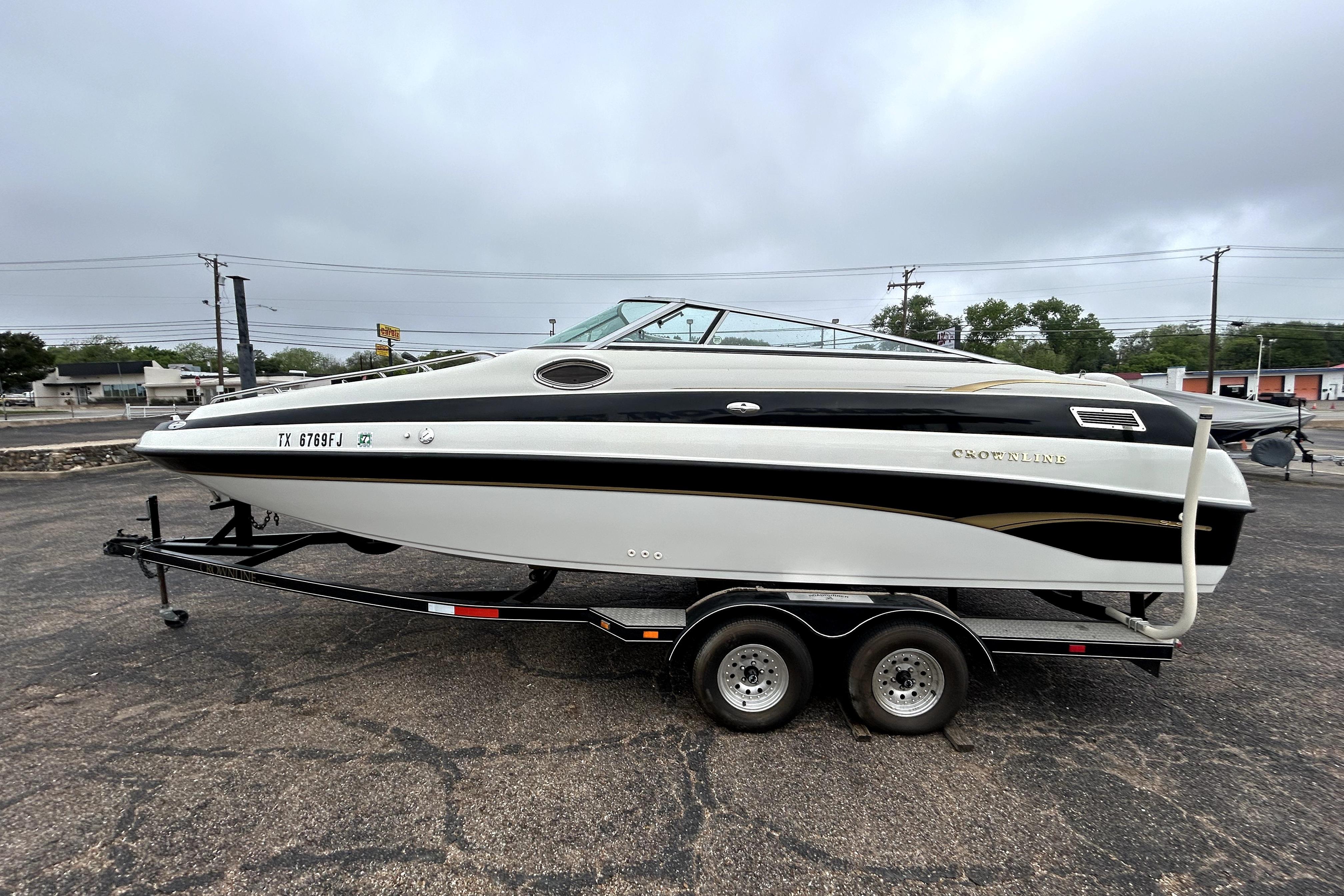 2001 Crownline 239 DB boat on trailer, parked outdoors under cloudy sky.
