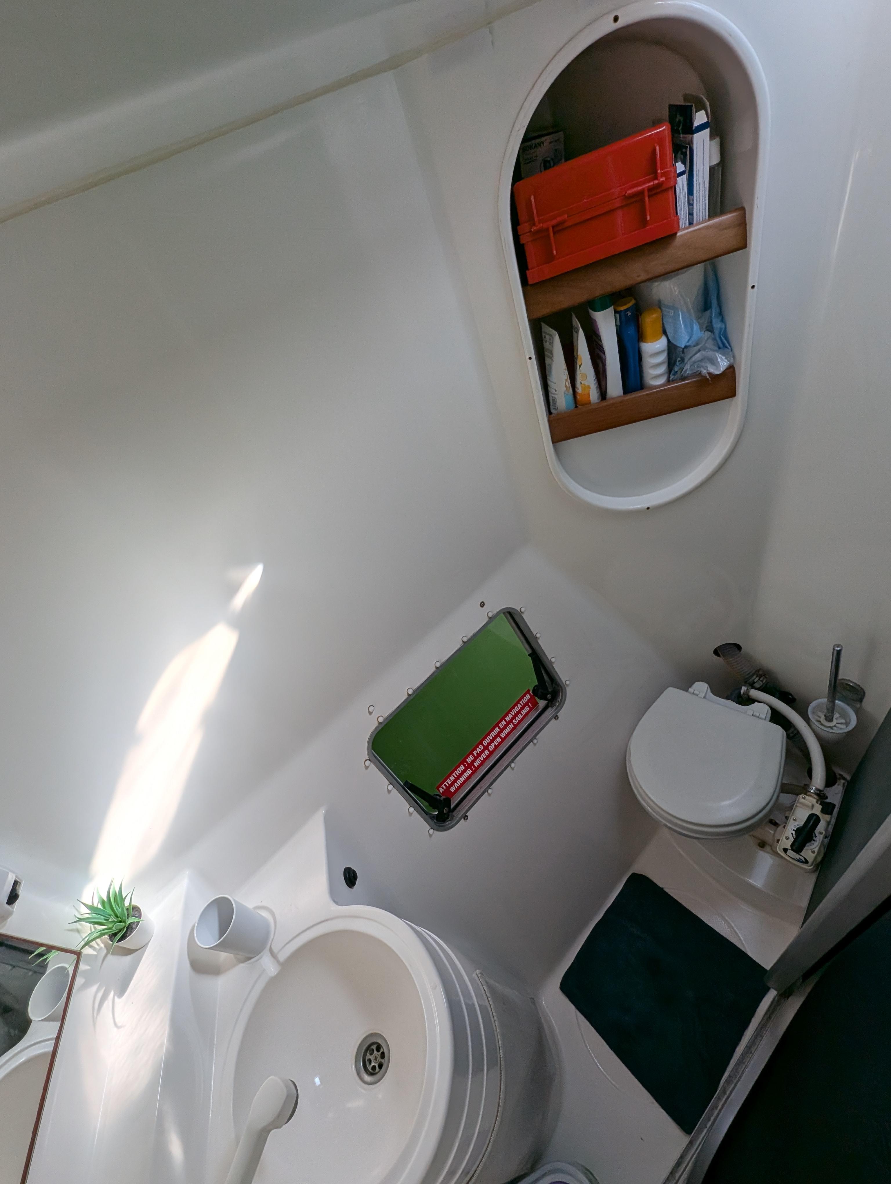 1999 Fountaine Pajot Athena 38 bathroom with sink, toilet, and storage shelves.