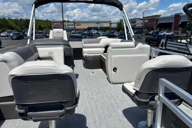 2026 Sun Tracker Fishin' Barge 20 DLX pontoon boat interior with seating, parked in a lot.