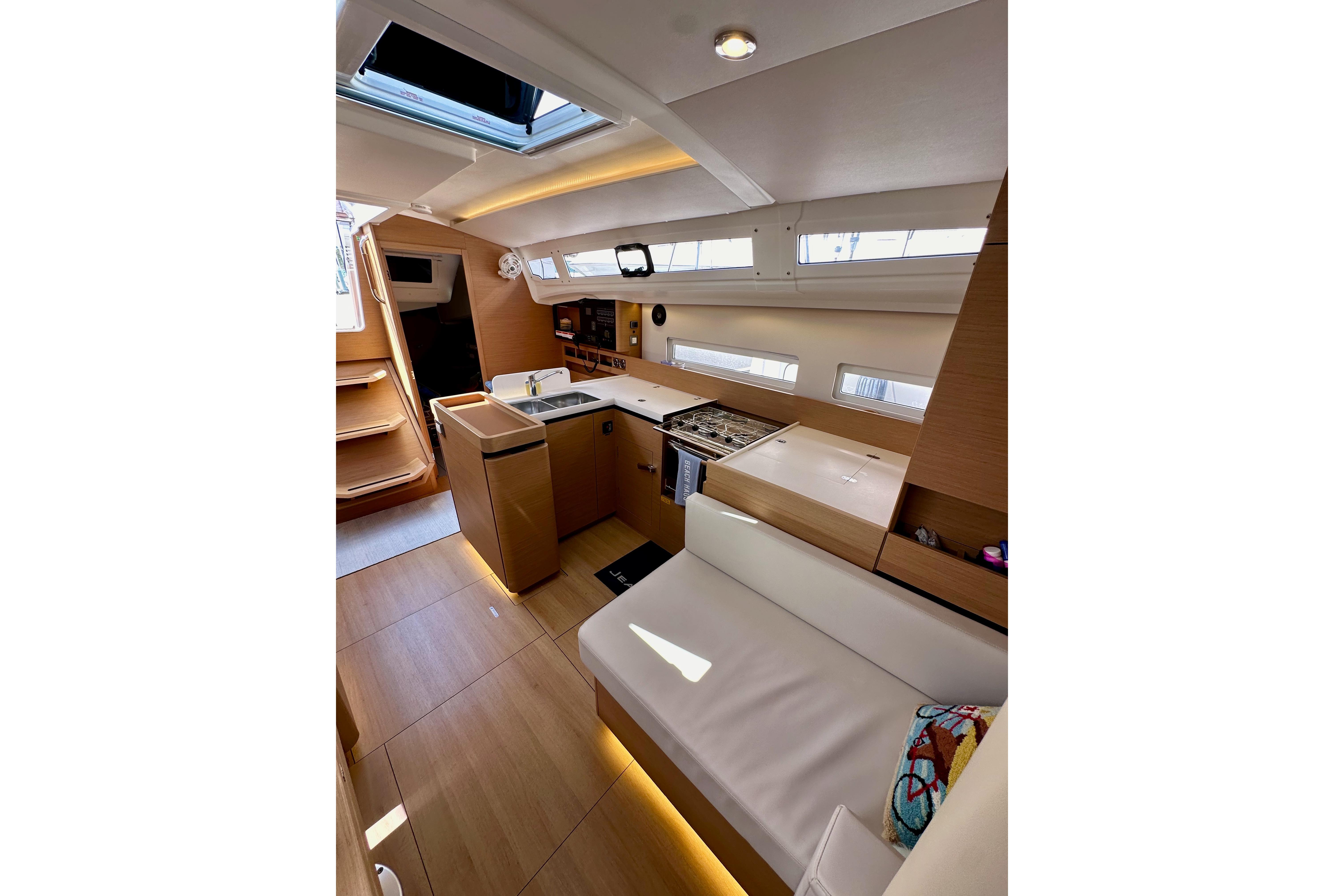 Interior of 2024 Jeanneau Sun Odyssey 410 yacht, featuring modern kitchen and seating area.