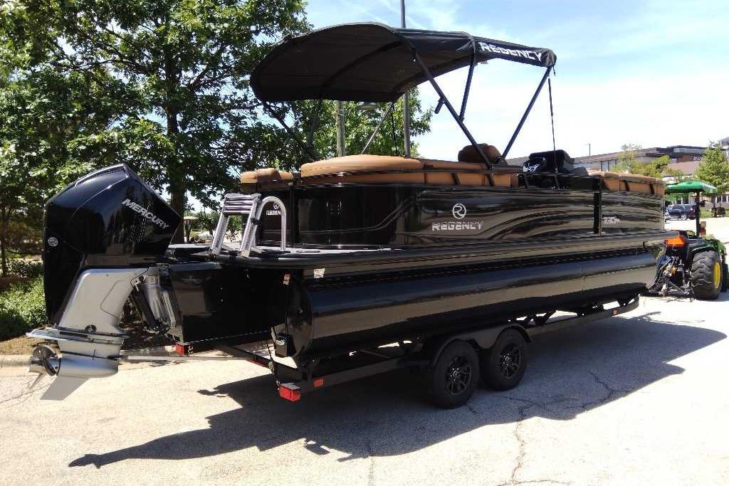 2026 Regency 230 DL pontoon boat with Mercury engine on trailer, parked outdoors.