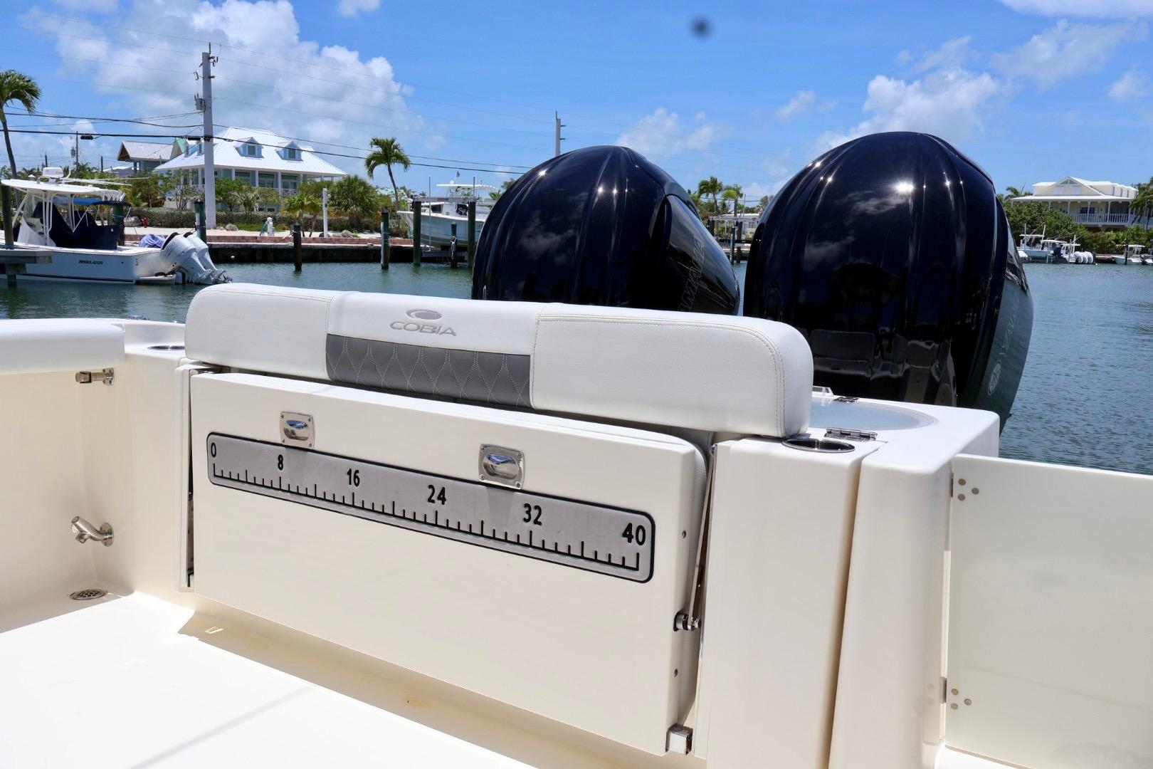 2022 Cobia 301 Center Console boat with dual engines, docked in a sunny marina.