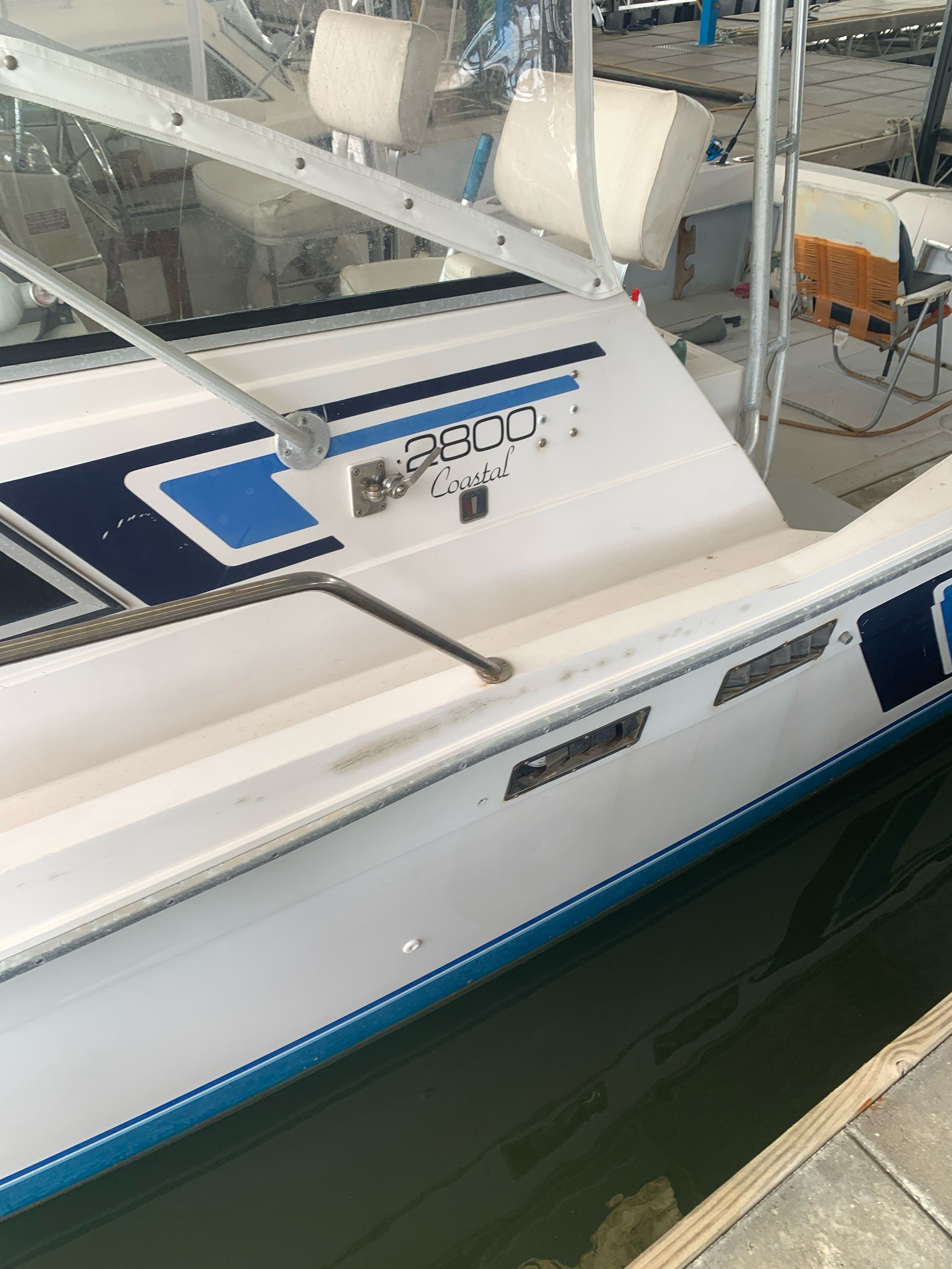 A 1987 Wellcraft Coastal boat docked, featuring blue and white accents and a covered area.
