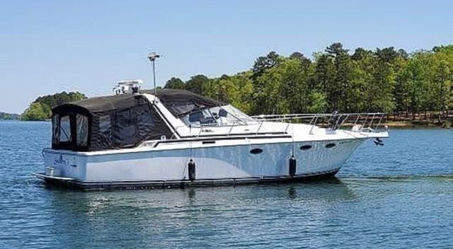 A white motorboat, Trojan 370 Express from 1989, cruising on a calm lake.