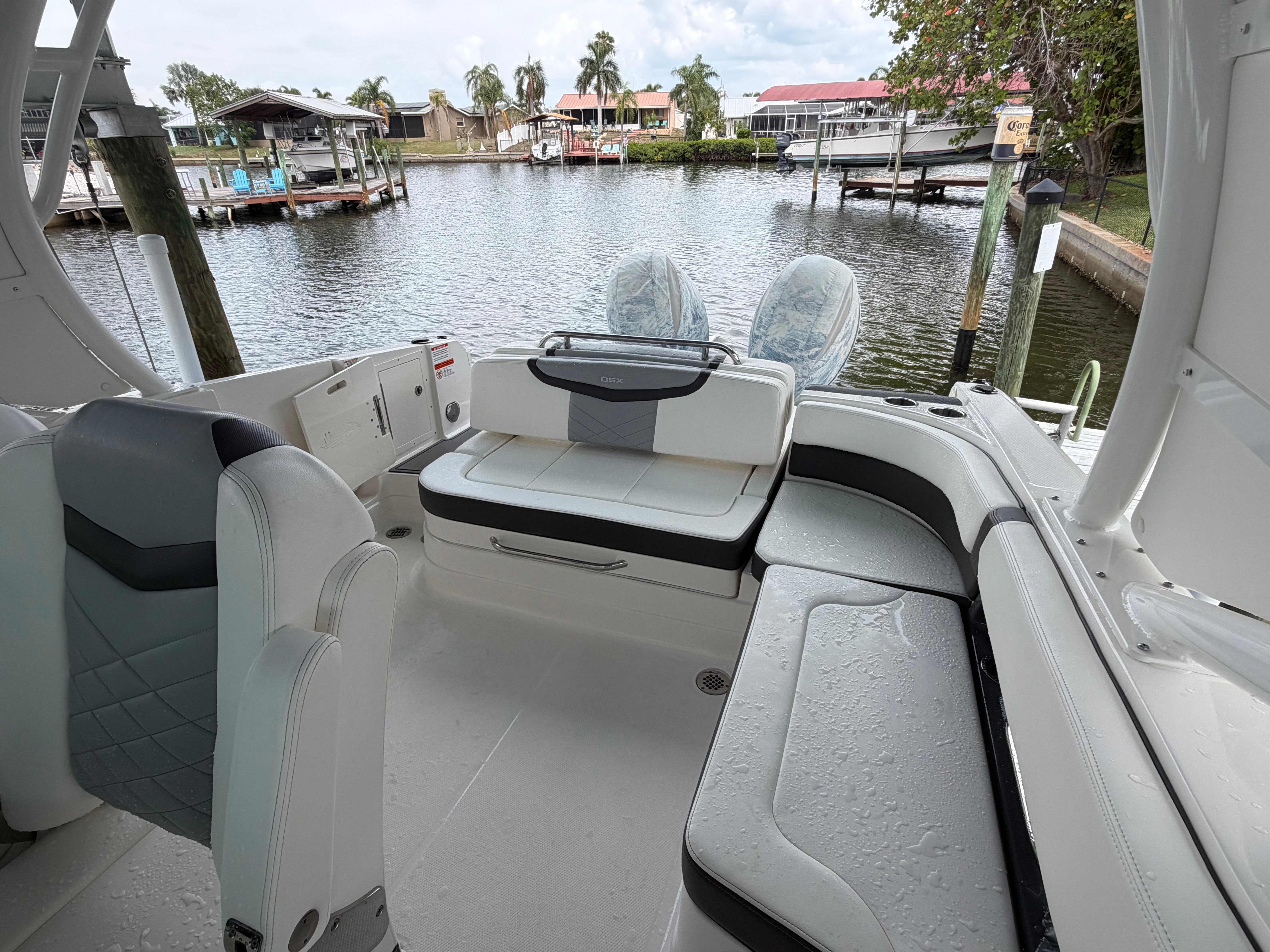 A modern boat with sleek seating and an open deck, docked at a calm harbor.