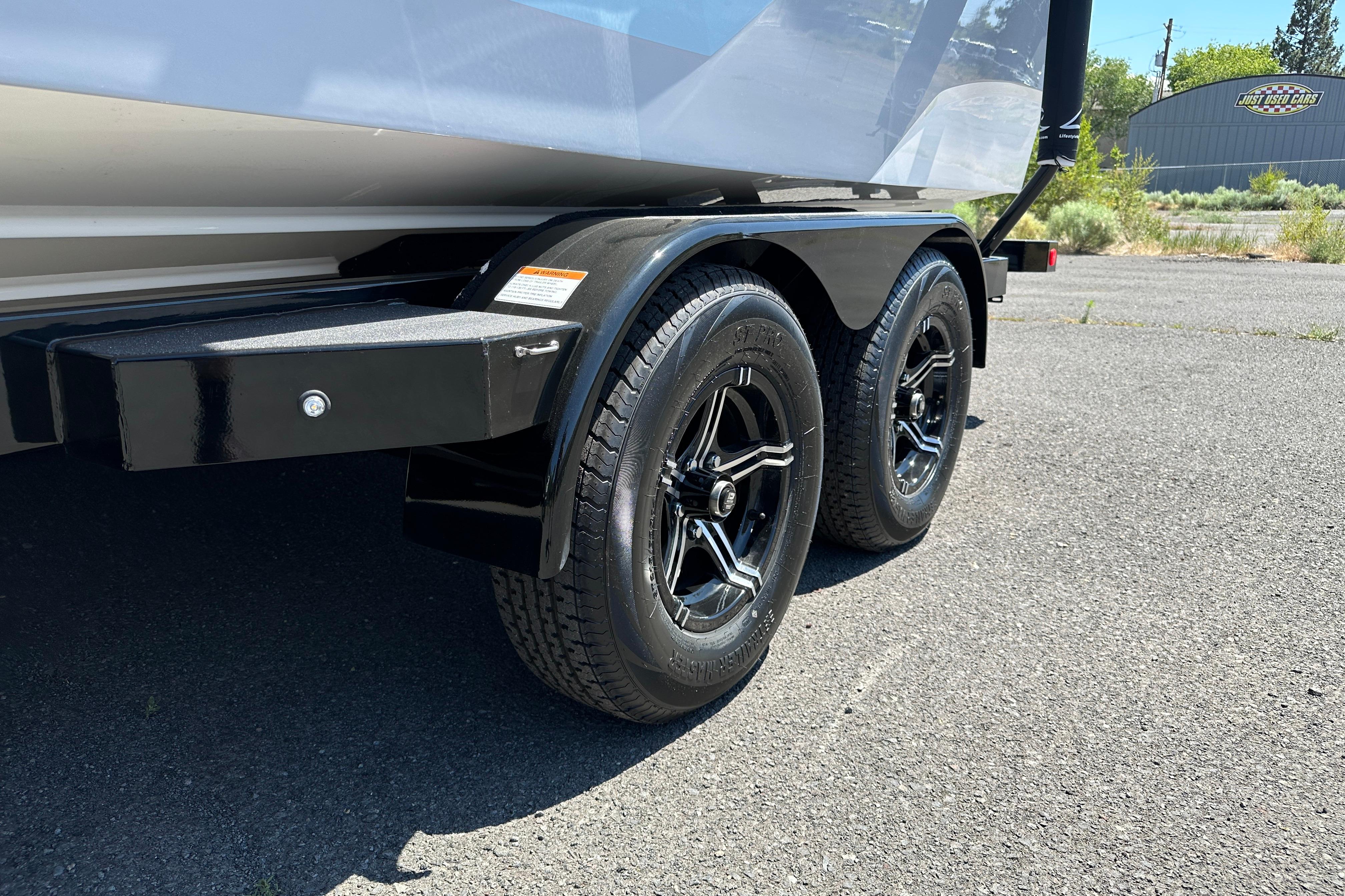 2023 MasterCraft NXT23 trailer with dual black wheels on asphalt surface.