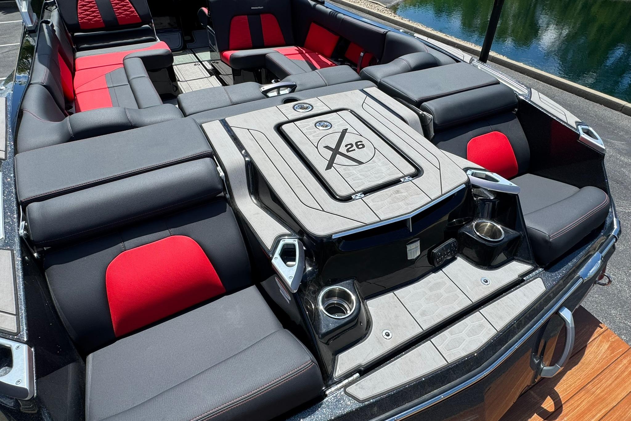 2021 MasterCraft X26 boat interior with red and gray seating, cup holders, and sleek design.