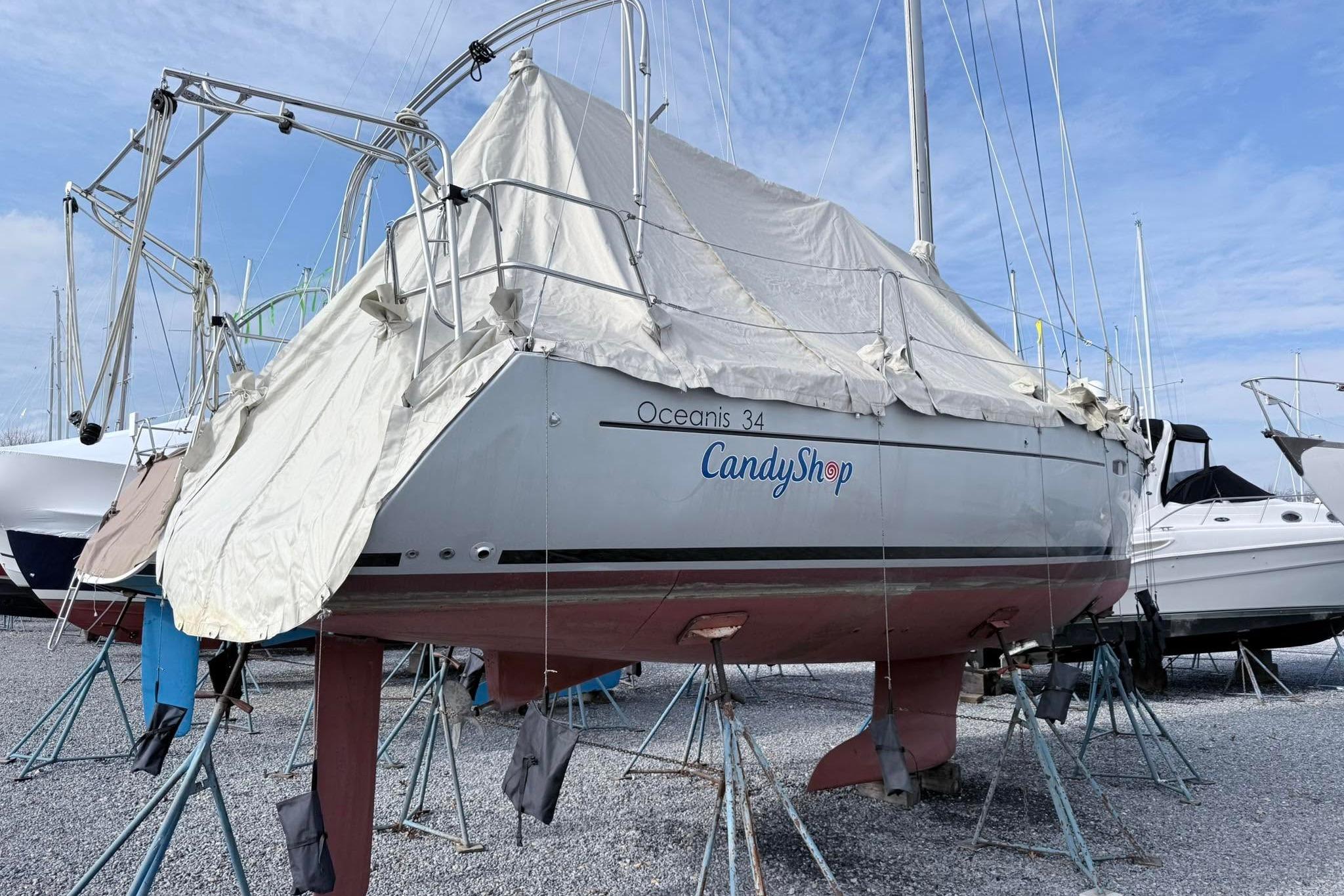 2015 Beneteau Oceanis 34 sailboat, named "CandyShop," covered and docked on land.