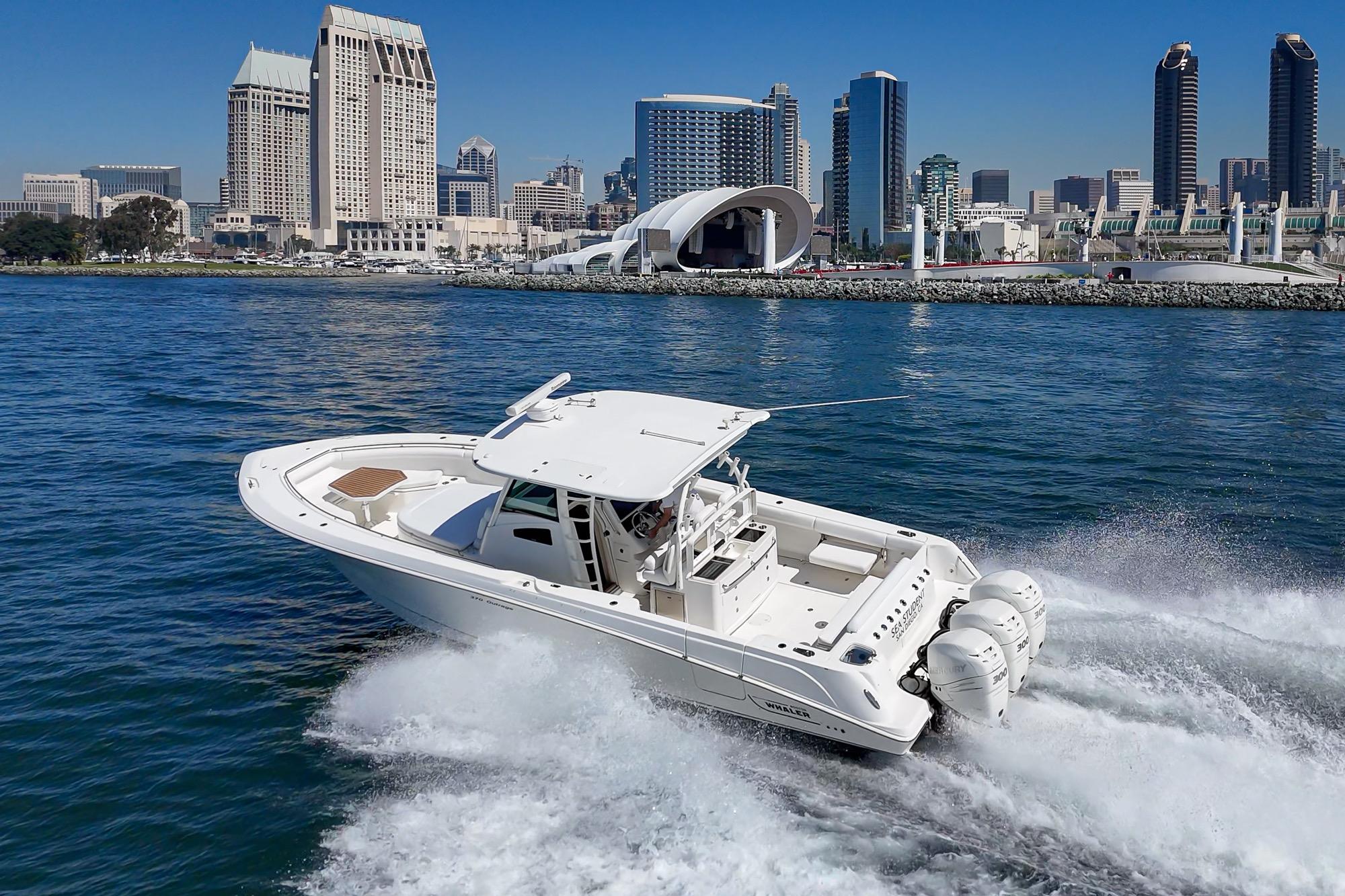 2015 Boston Whaler 370 Outrage cruising near city skyline on a sunny day.