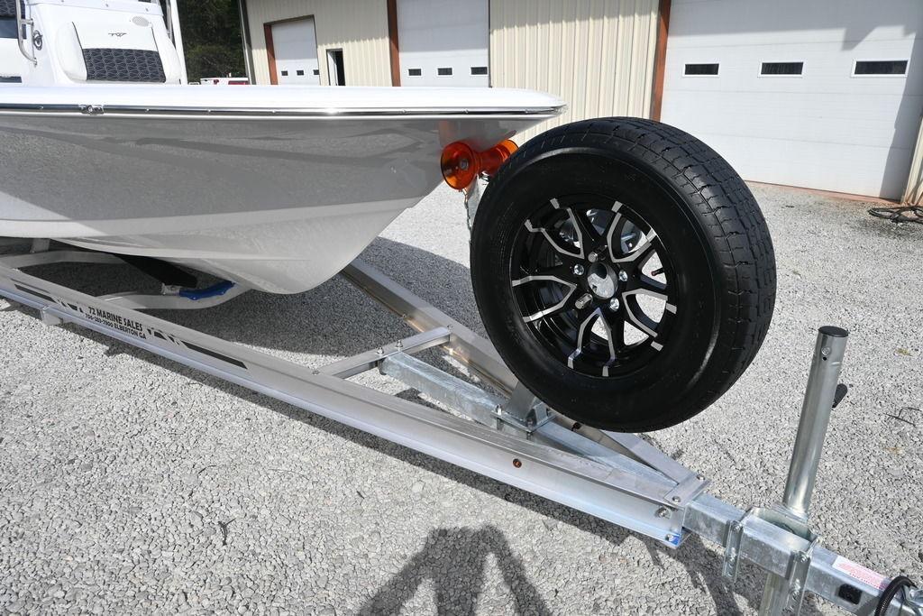 2026 Tidewater 1910 Bay Max boat on trailer with spare tire, parked outside garage.