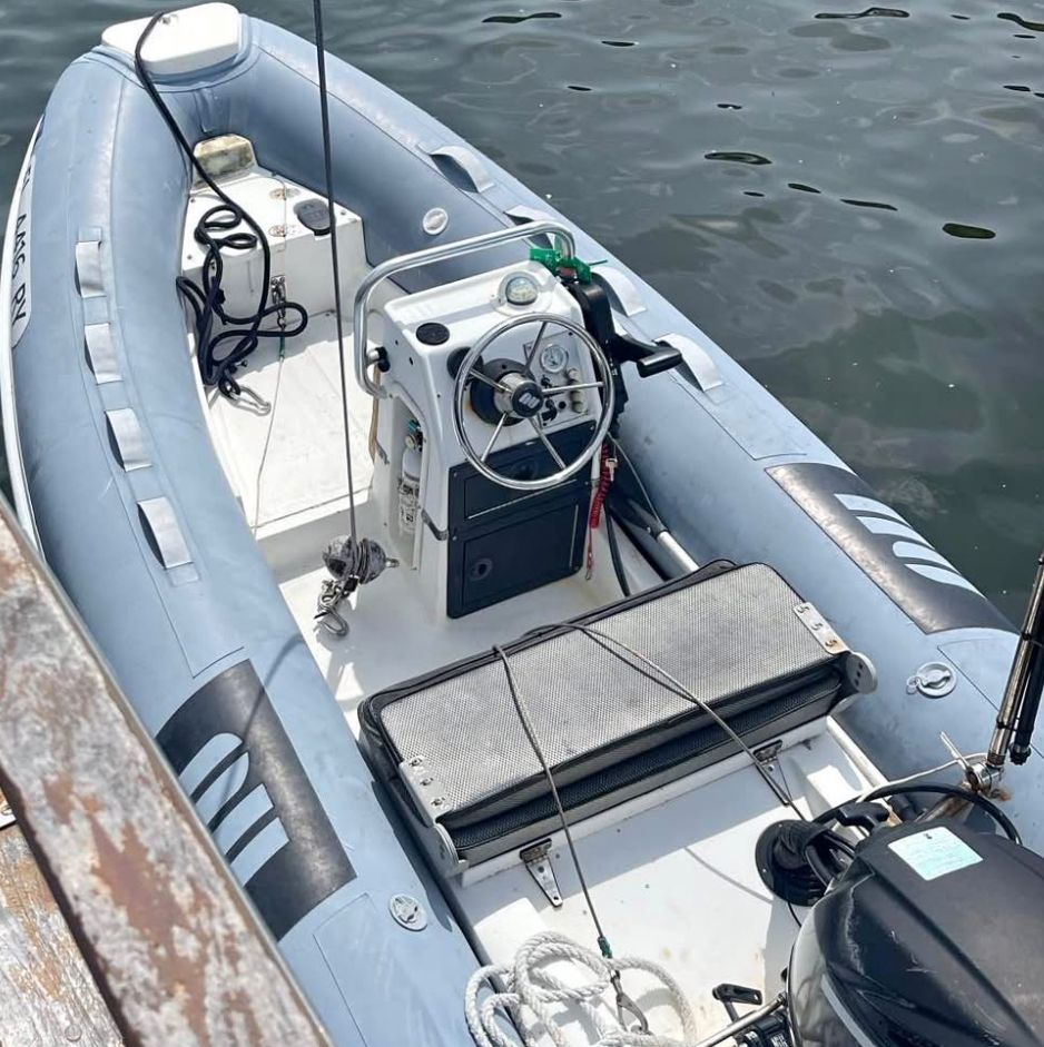 An inflatable boat with a steering console and motor on calm water.