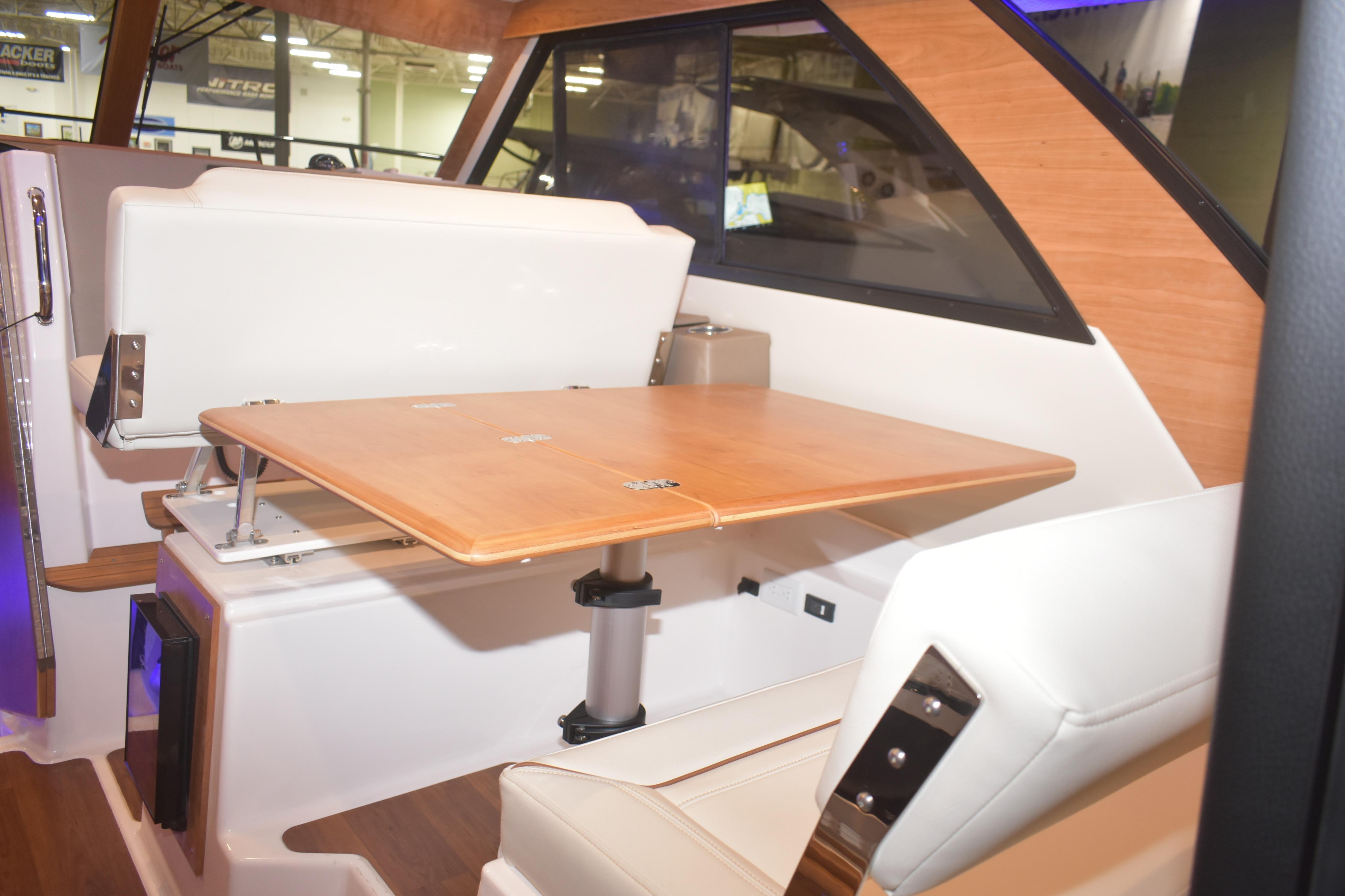 Interior of 2026 Cutwater C-32 CB boat with wooden table and white seating.