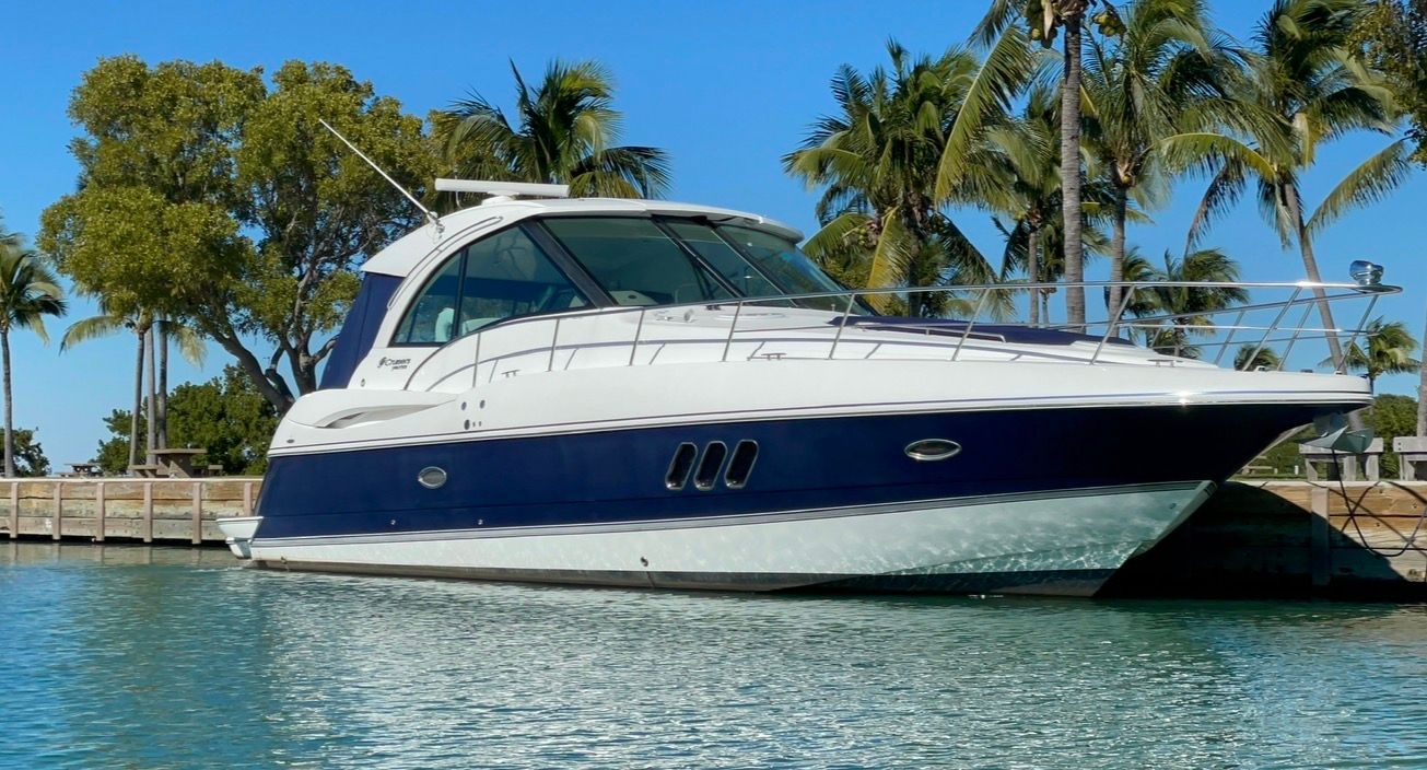 2012 Cruisers Yachts 430 Sports Coupe on water, surrounded by palm trees.