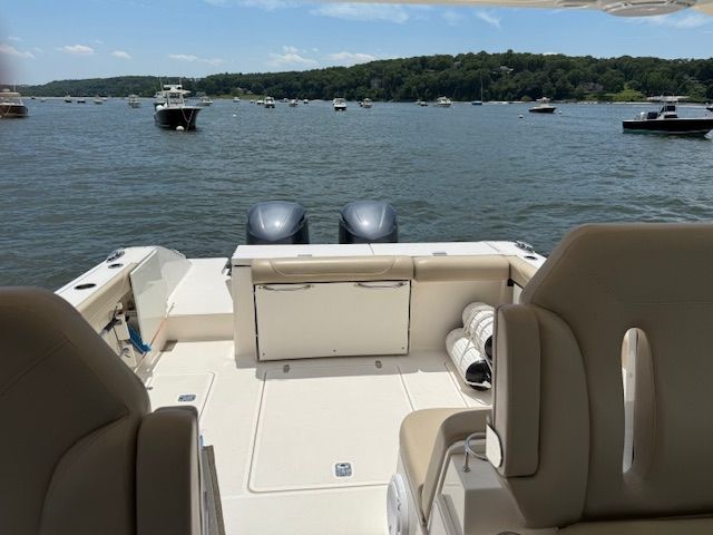 A 2015 Pursuit DC 325 Dual Console boat on calm waters with several boats around.