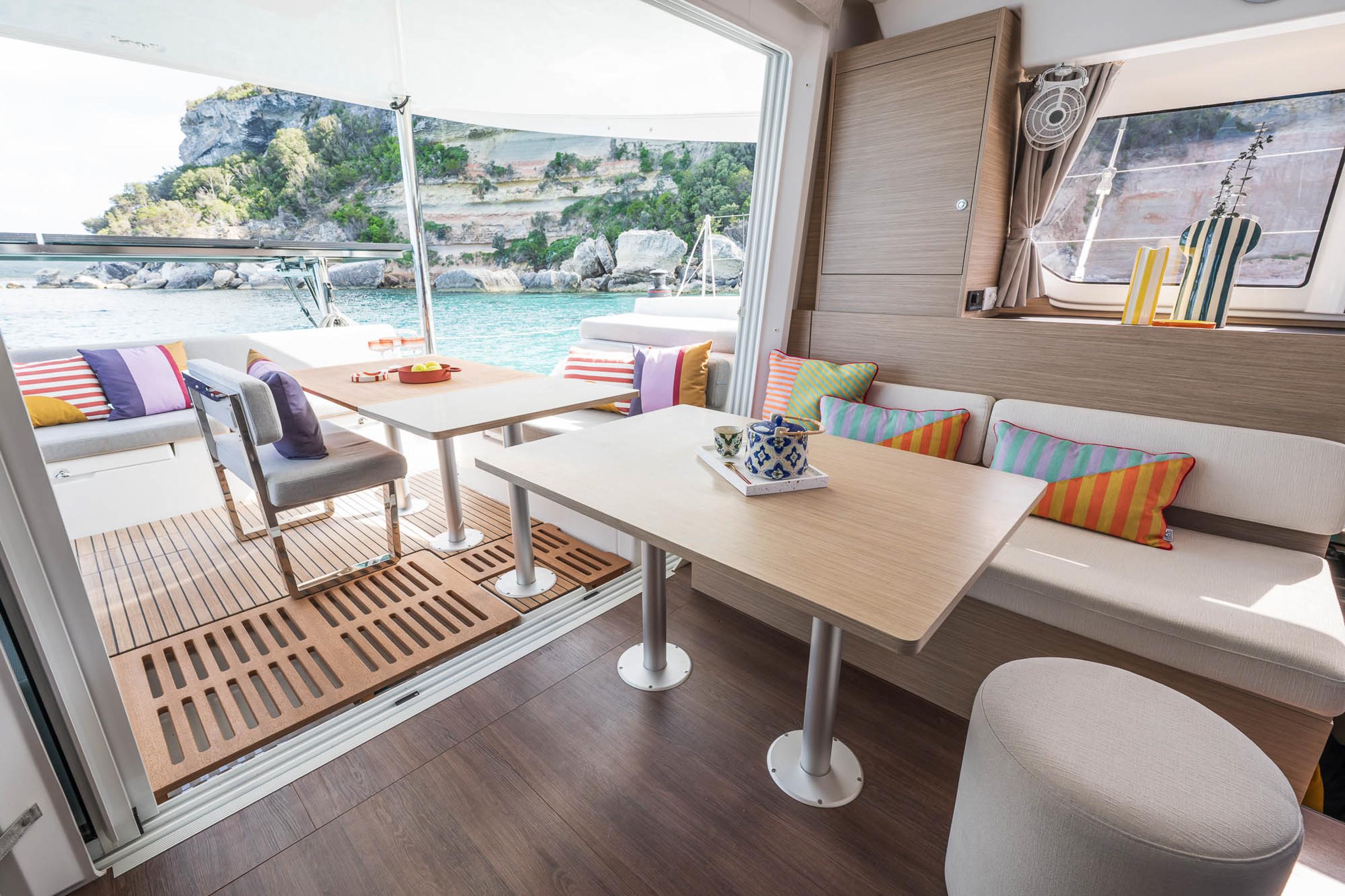 Luxurious interior of 2025 Lagoon 38 catamaran with colorful cushions and scenic ocean view.
